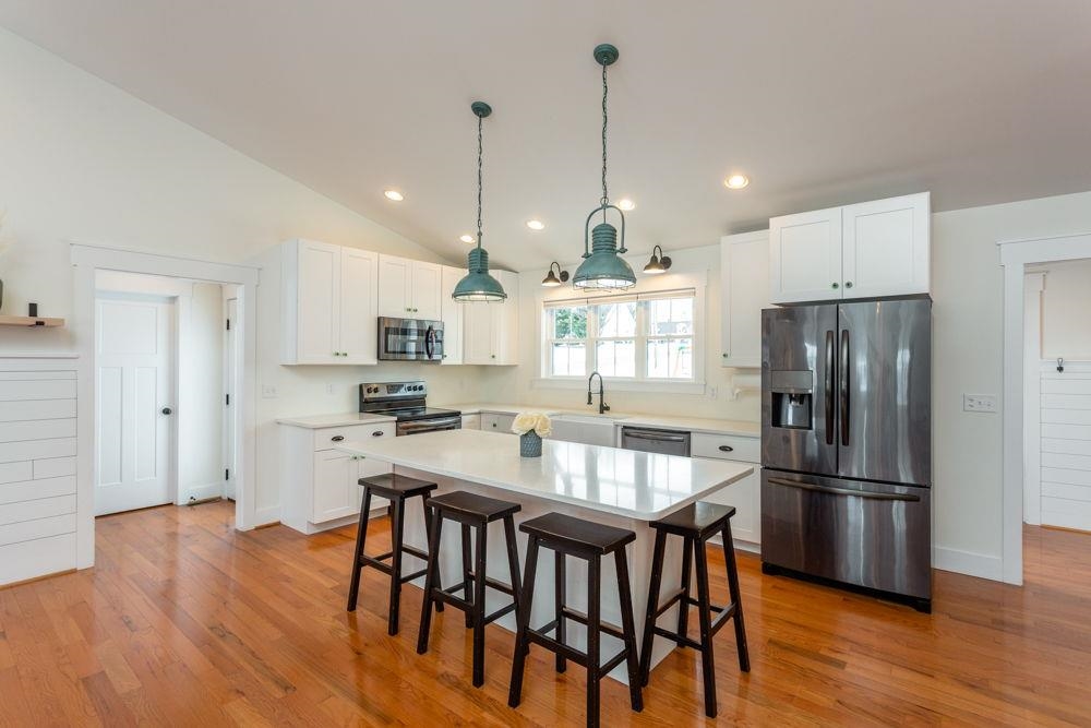 with stainless steel appliances, white cabinets and white granite.