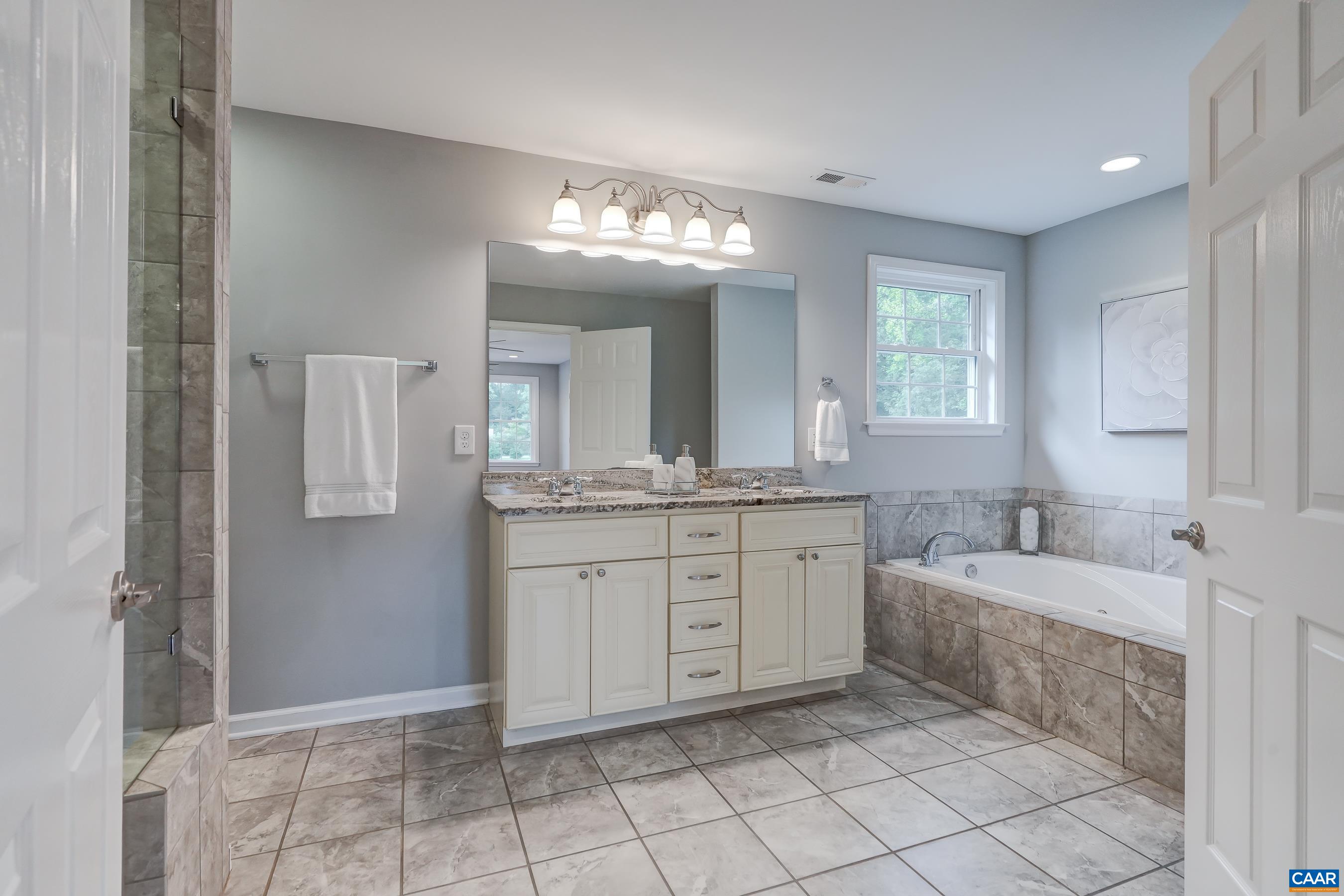 Primary bathroom with dual sink vanity, deep jetted soaking tub and walk-in shower.