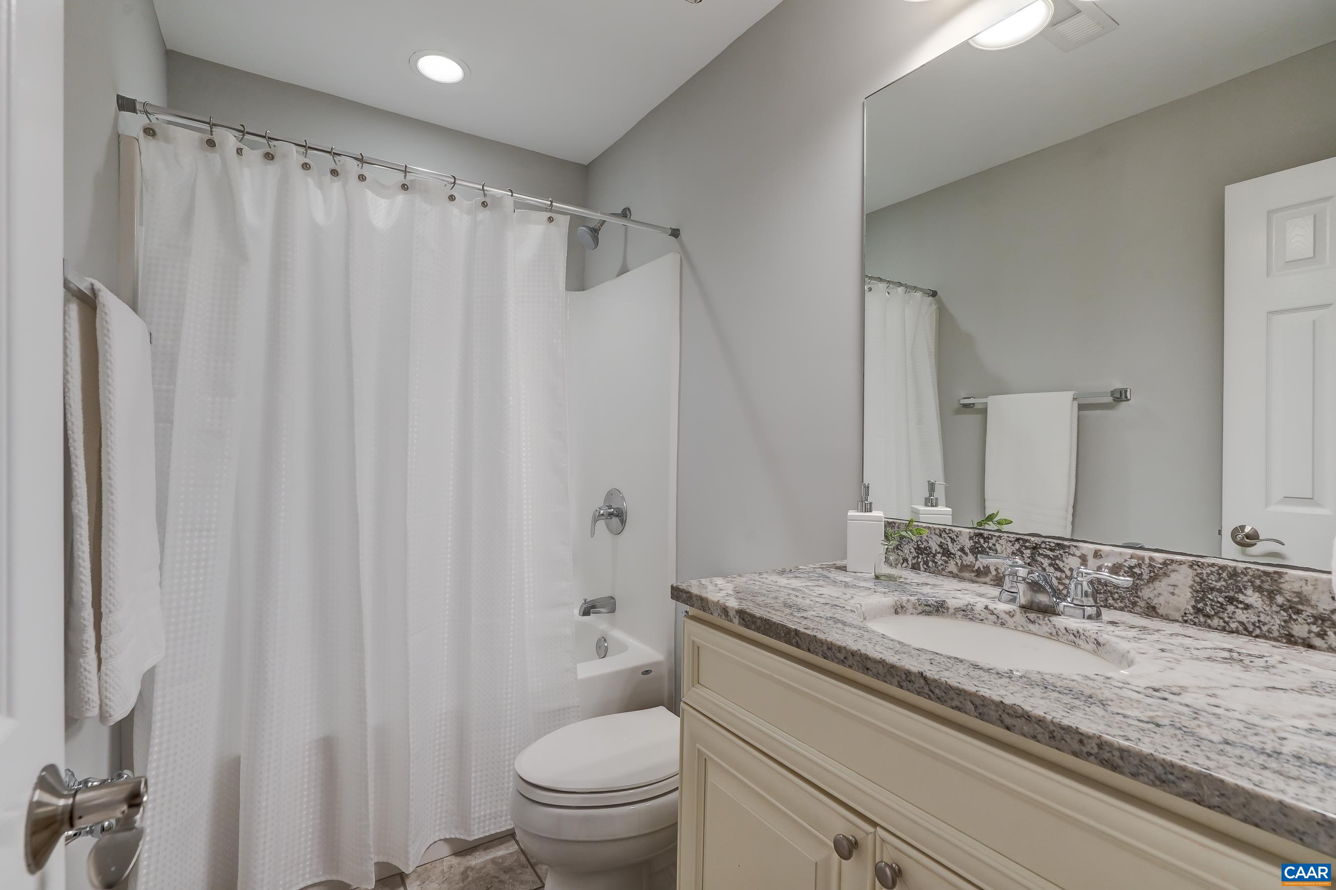 Full hall bathroom with sleek granite counters.