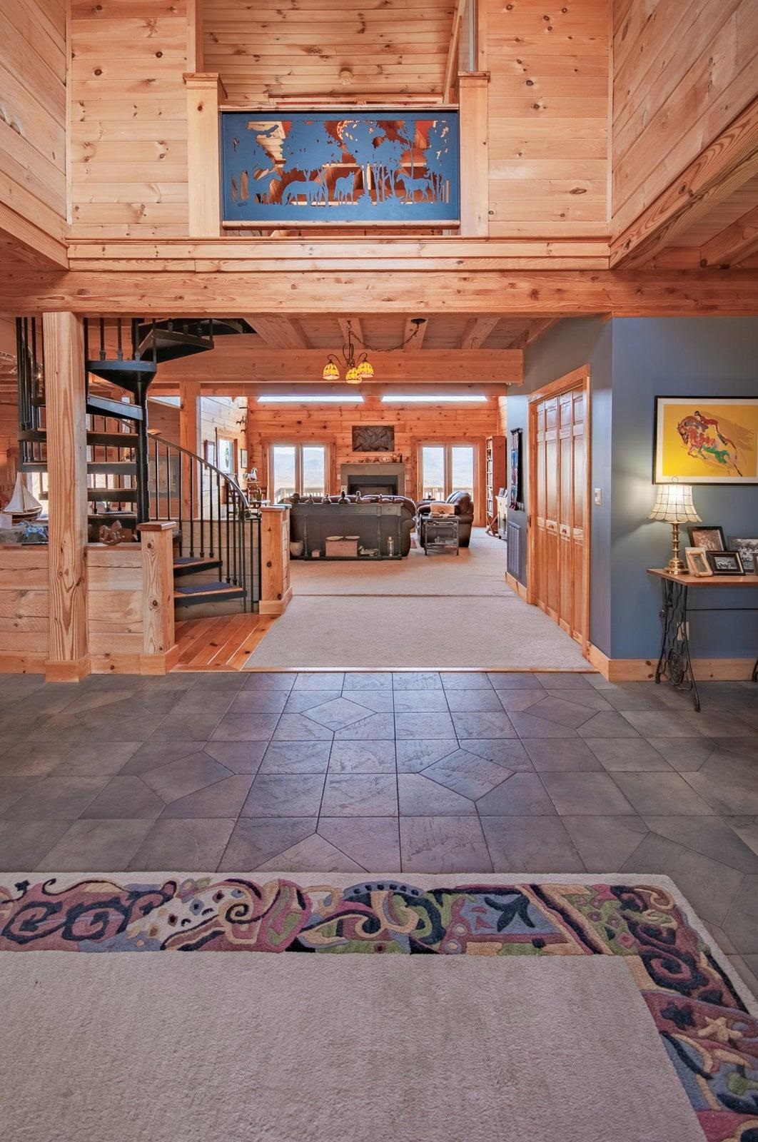 Entrance hallway. Wrought-iron spiral staircase to both 2nd floor and to the basement. Access the kitchen on left, great room straight ahead. 2nd floor balcony is above.