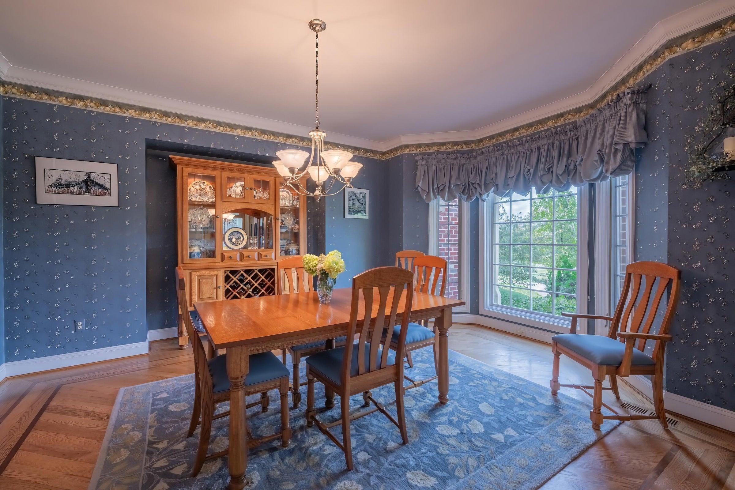 Beautifully decorated dining room with crown molding, floor to ceiling windows, oak floors with walnut inlay.