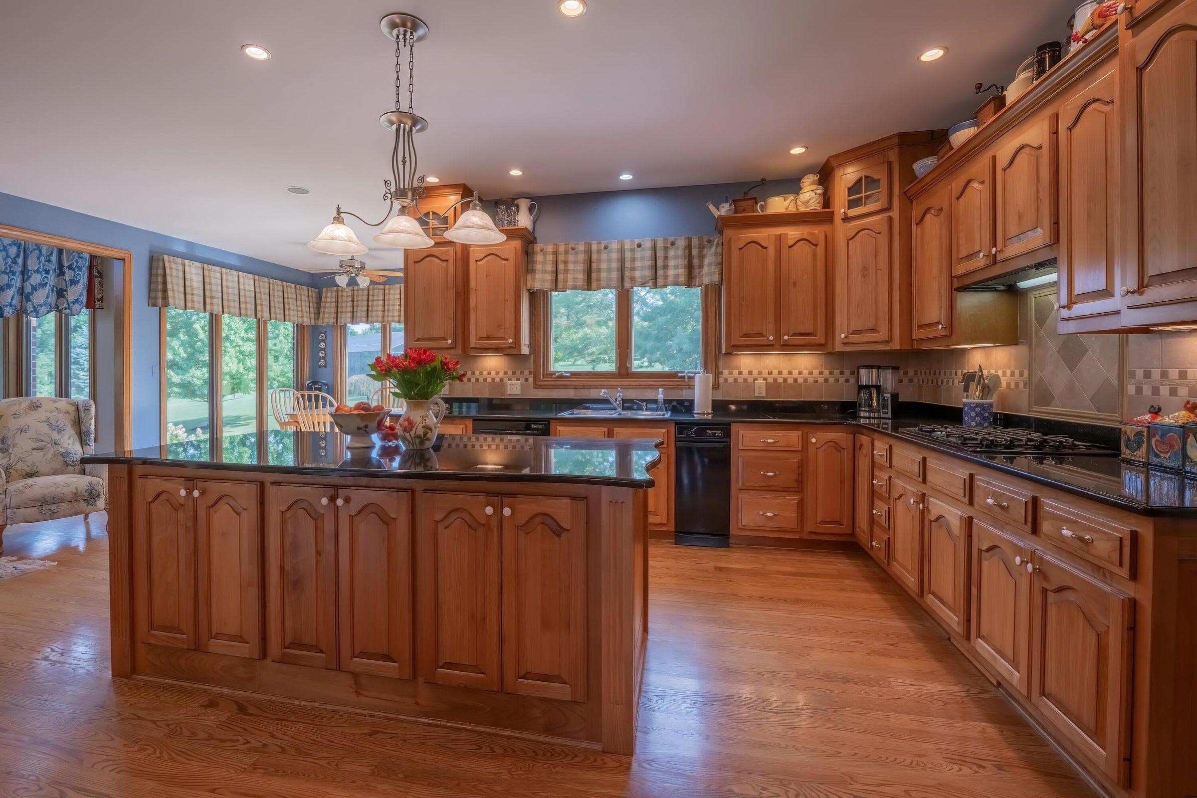 Enter the kitchen from the hallway. Oak floors, Black granite counters, red birch custom cabinets.