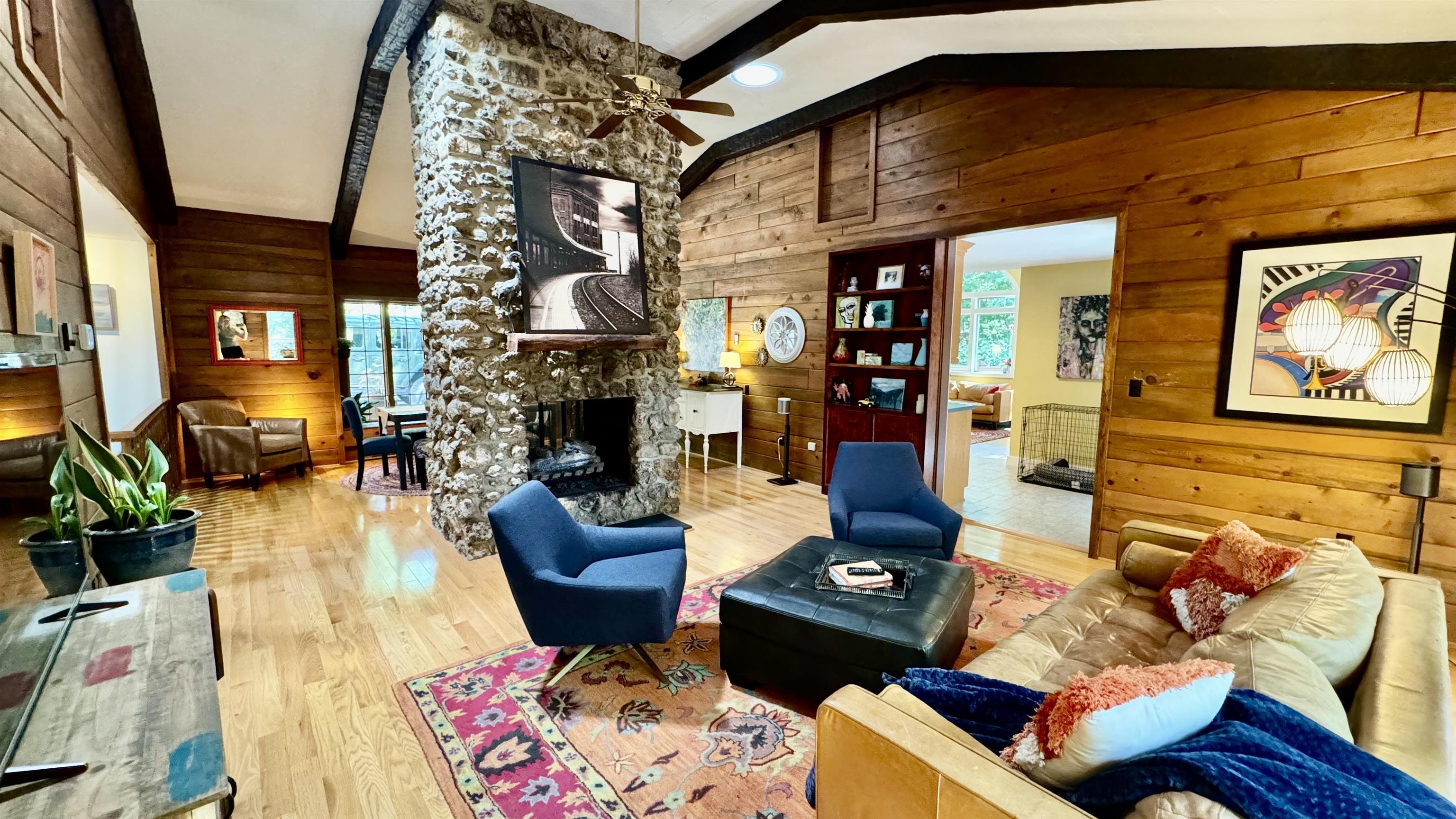 Living room with floor-to-ceiling stone fireplace and hardwood paneling.