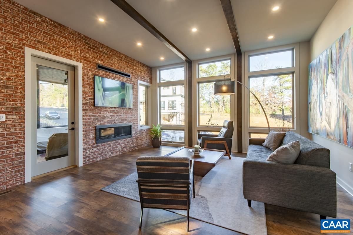 Stunning great room features exposed brick walls and beams, and wall of picture windows.