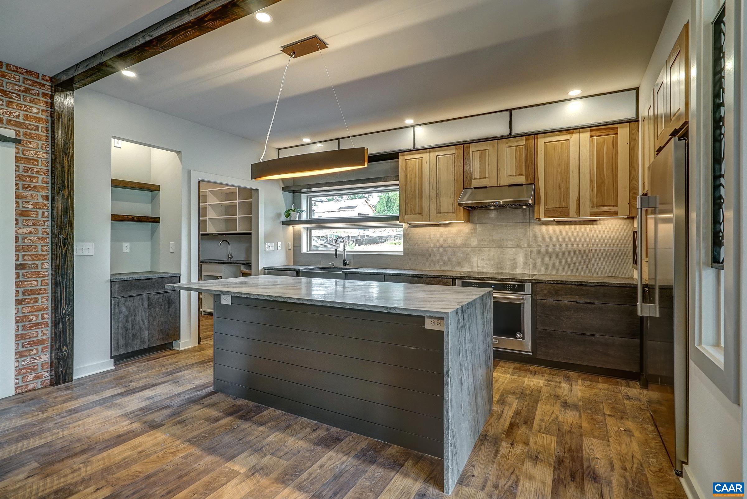 Beautiful kitchen is a chef's dream! Exposed shelving and hickory cabinets with quartz waterfall island.