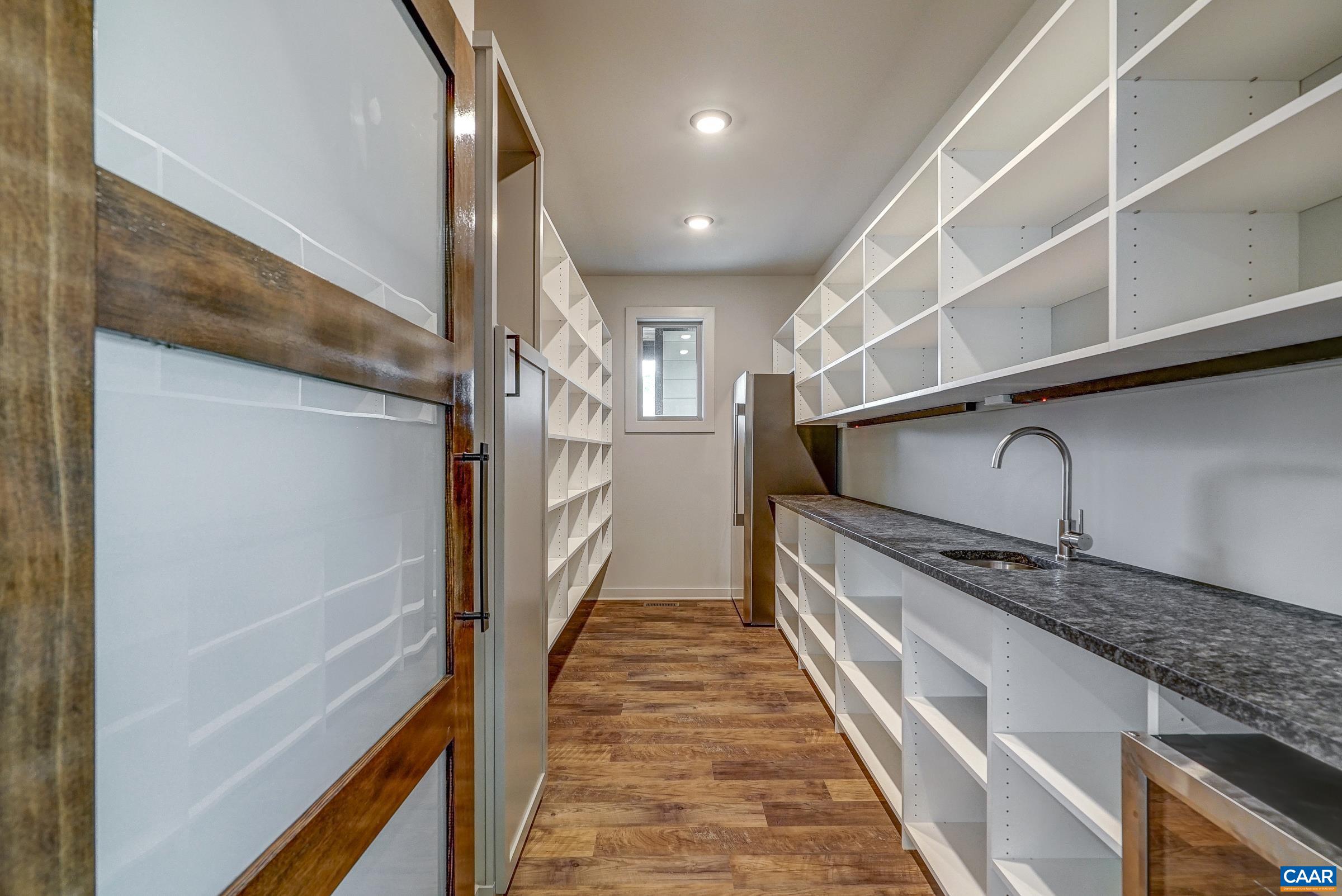 Walk in pantry with countertop for small appliances, wine cooler, and extra freezer.