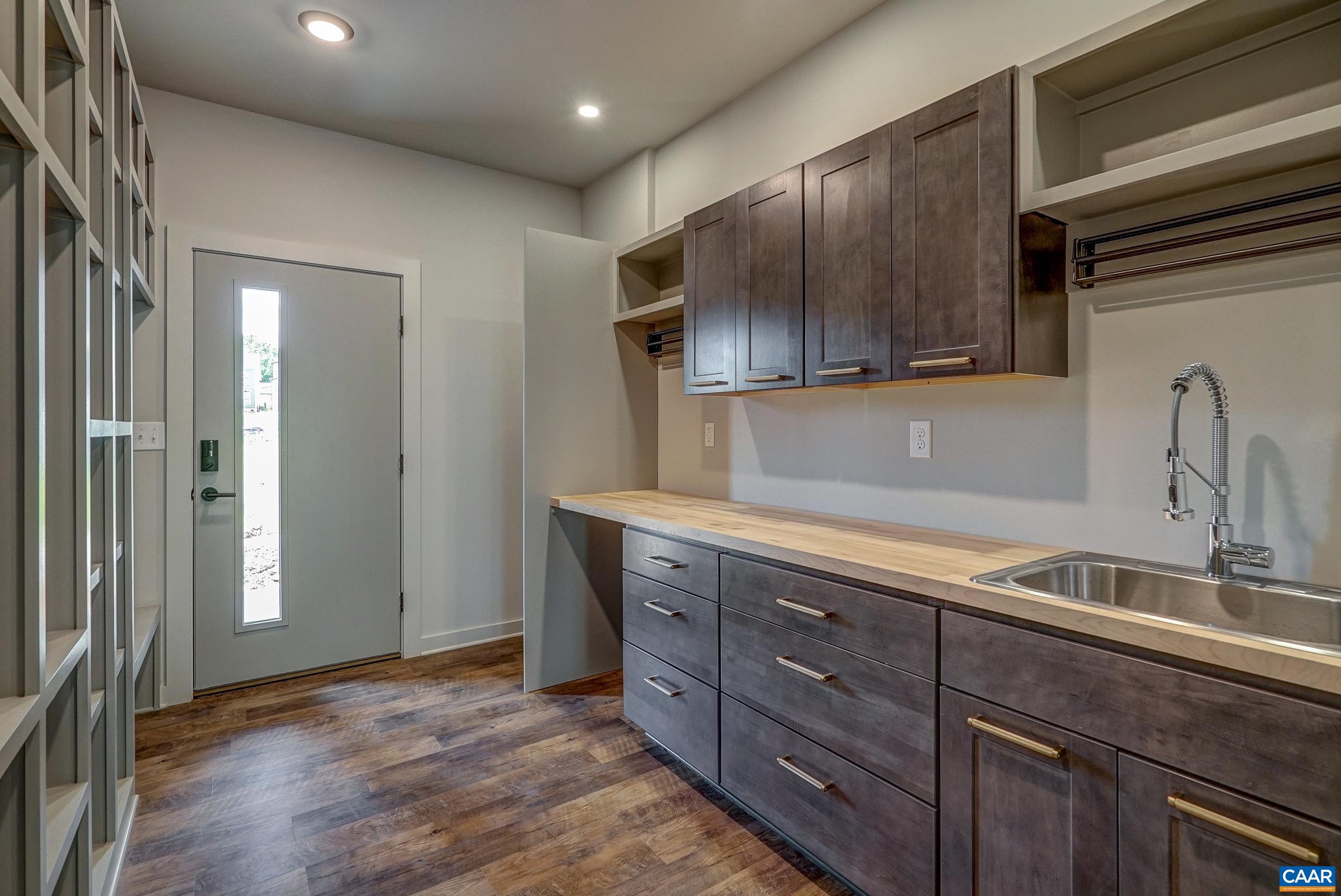 Mudroom features large utility sink and stacked washer/ dryer hookups.