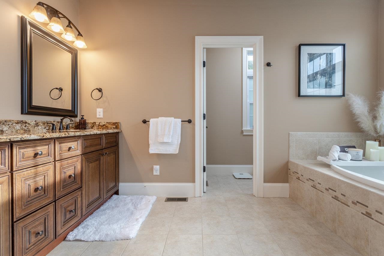 Luxuriate in this primary en-suite with large tub, tile shower, dual sink vanity, and enclosed lavatory