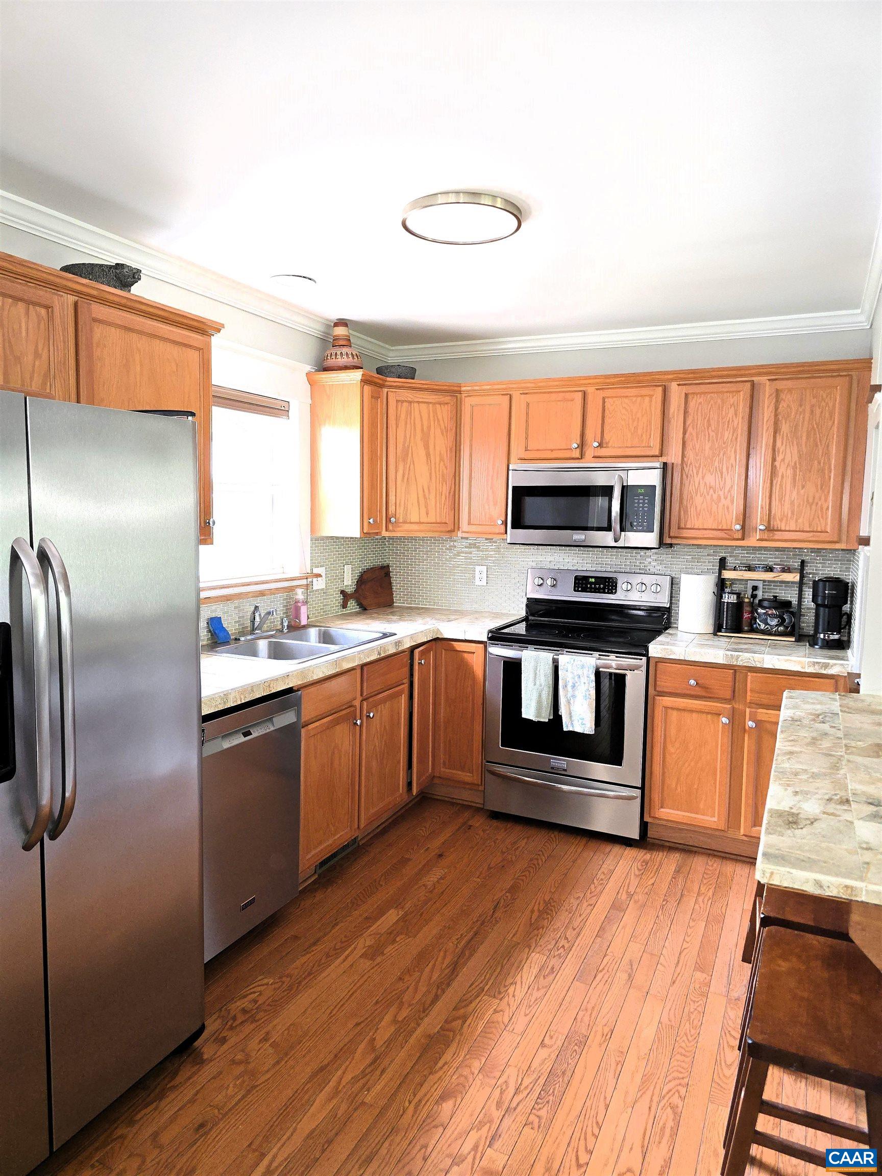 Kitchen featuring Hardwood floors, Oak cabinets, tiled counter tops, and stainless steel appliances.