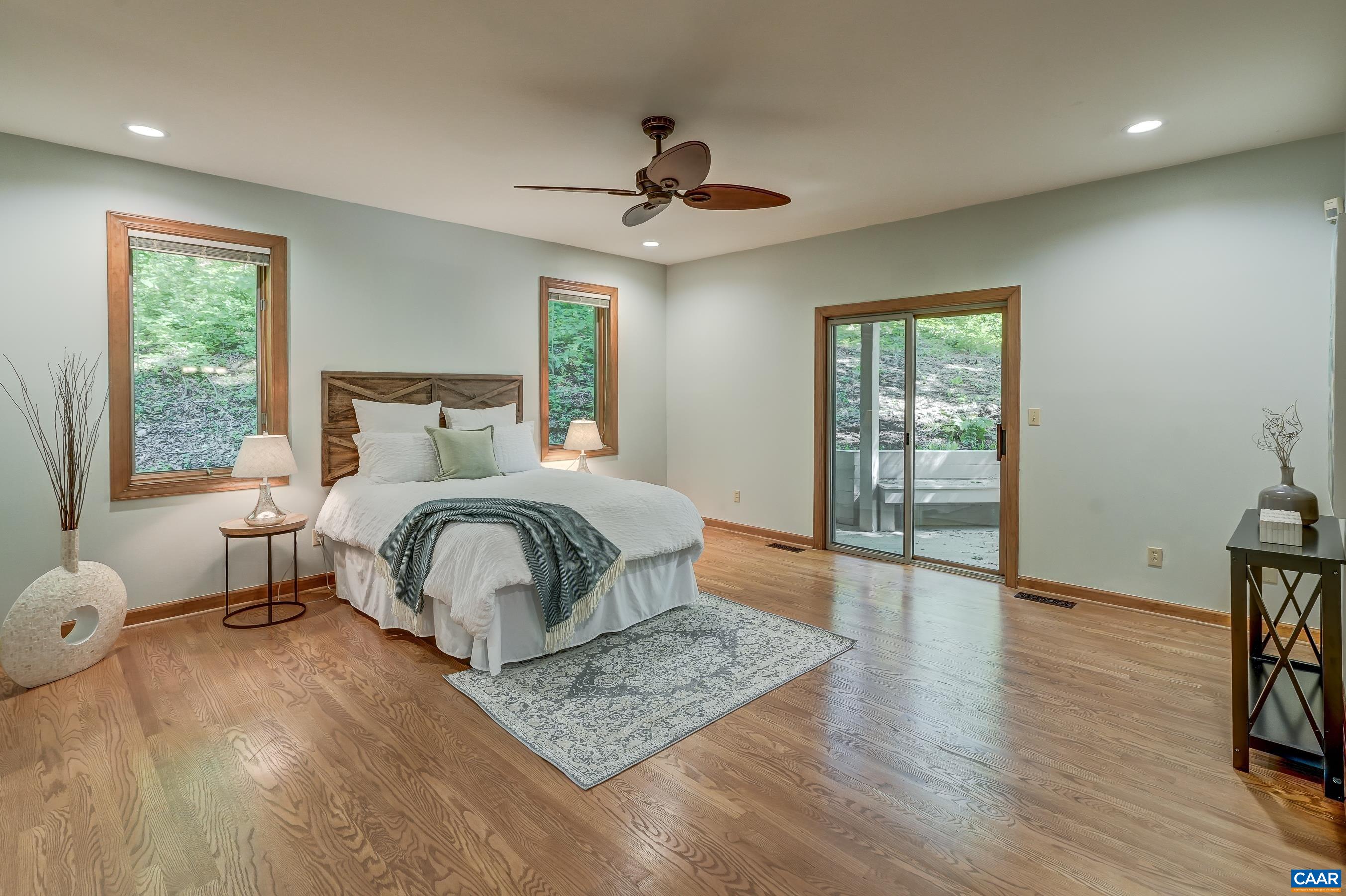 Primary suite on the main level with sliding doors to deck, two walk-in closets, and ensuite bathroom.
