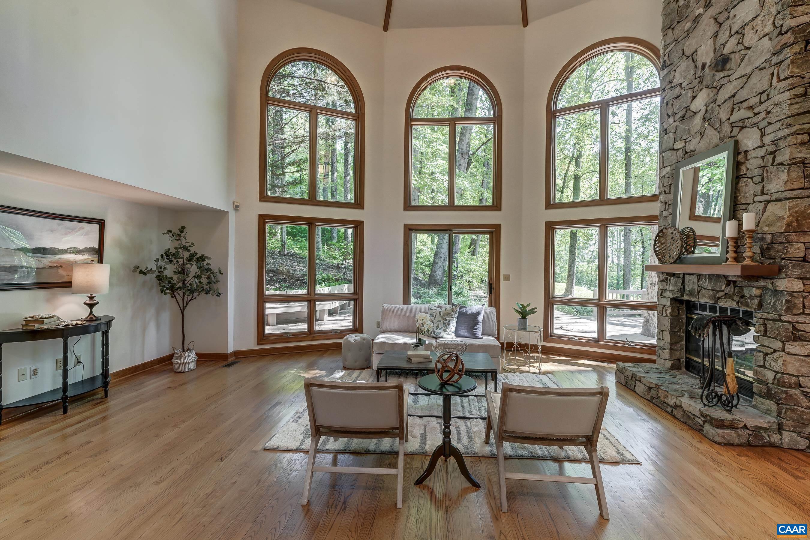 Vaulted great room with wall of windows, and stacked stone fireplace.