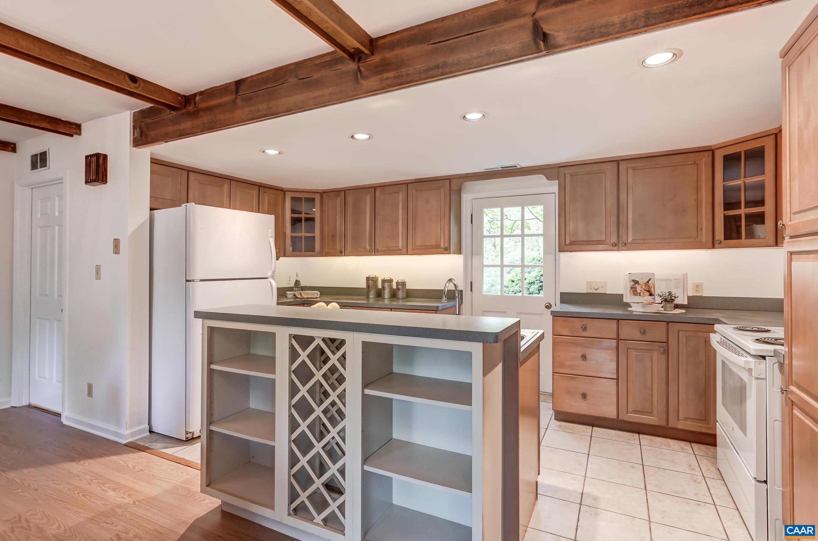 Updated kitchen features maple cabinets and white apppliances including a new stove and dishwasher.