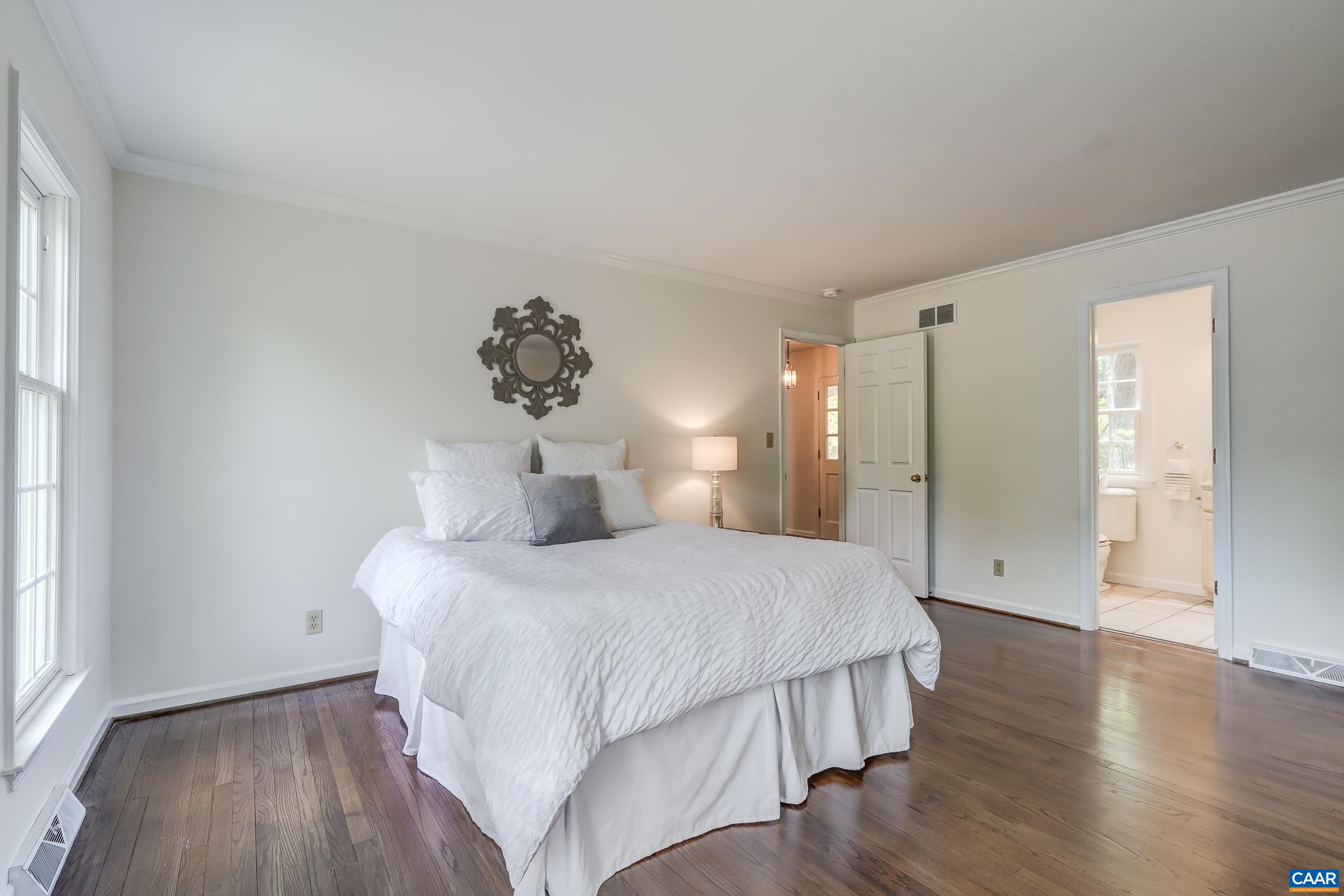 Primary bedroom with hardwood floors, walk in closet and ensuite bathroom.
