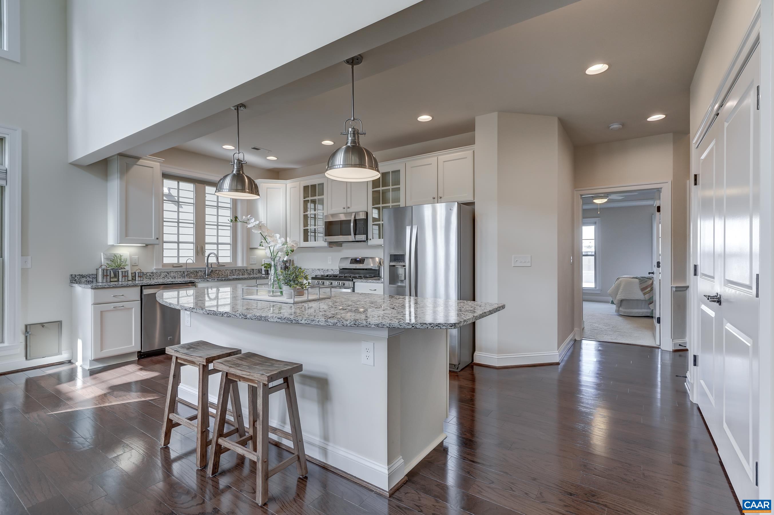 Bright and cheery kitchen features modern pendant lighting, granite countertops, and stainless steel appliances.