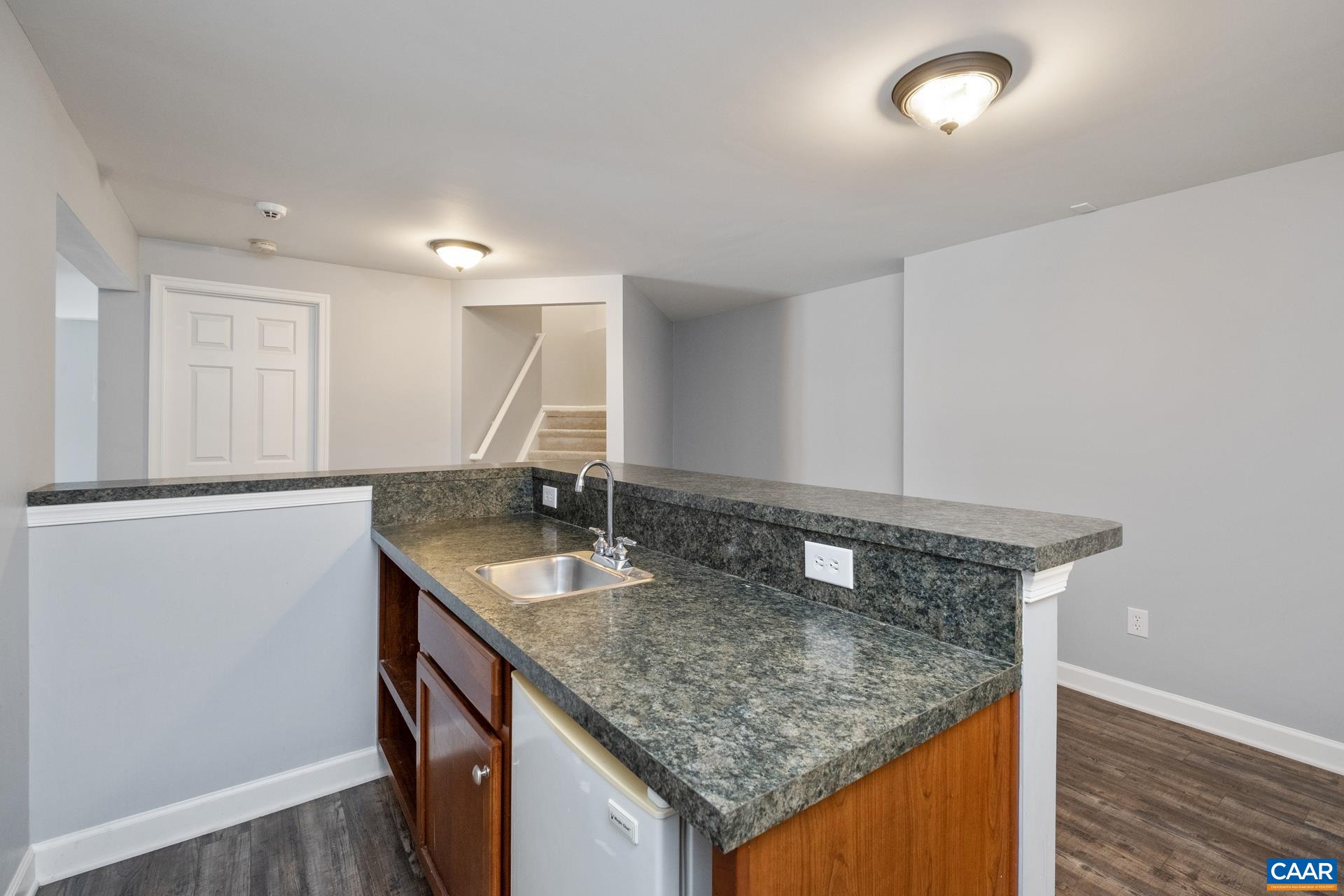 Bar area includes mini fridge, sink, and shelves.