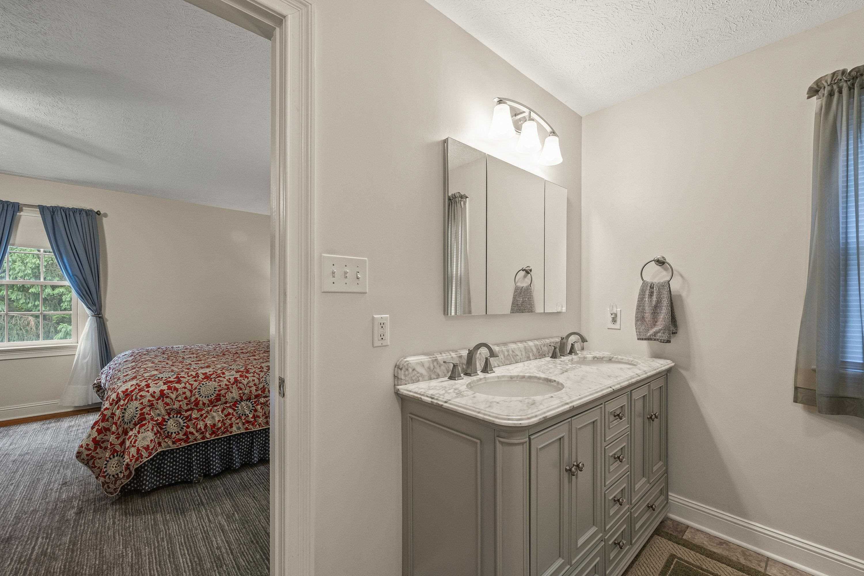The attached bathroom offers updates throughout.  This space features a whirlpool bathtub, stand-up shower, and dual vanities with storage cabinetry.