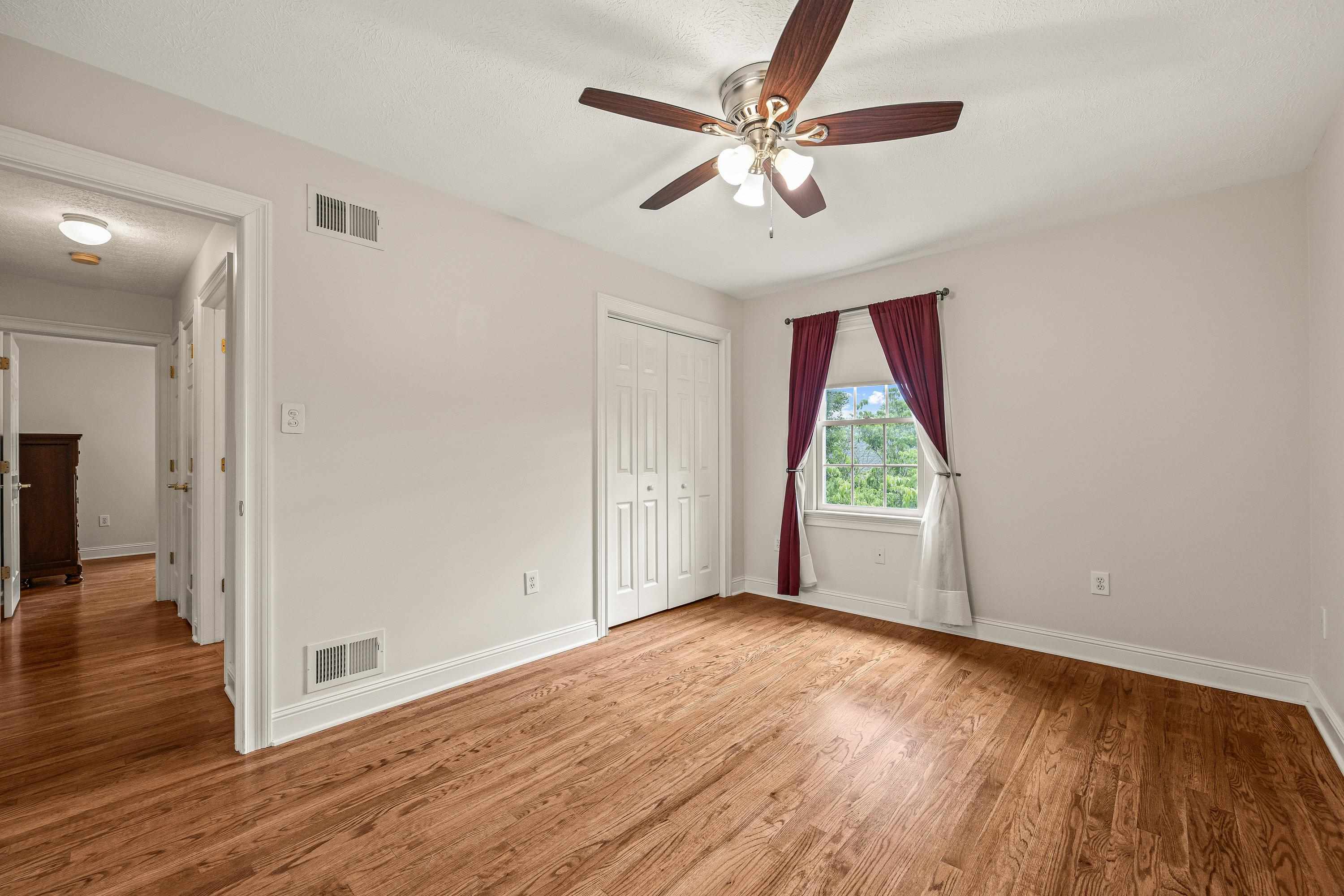 This third bedroom features hardwood flooring throughout, large windows, and a large closet space. All three bedrooms are located on the first floor of the home.