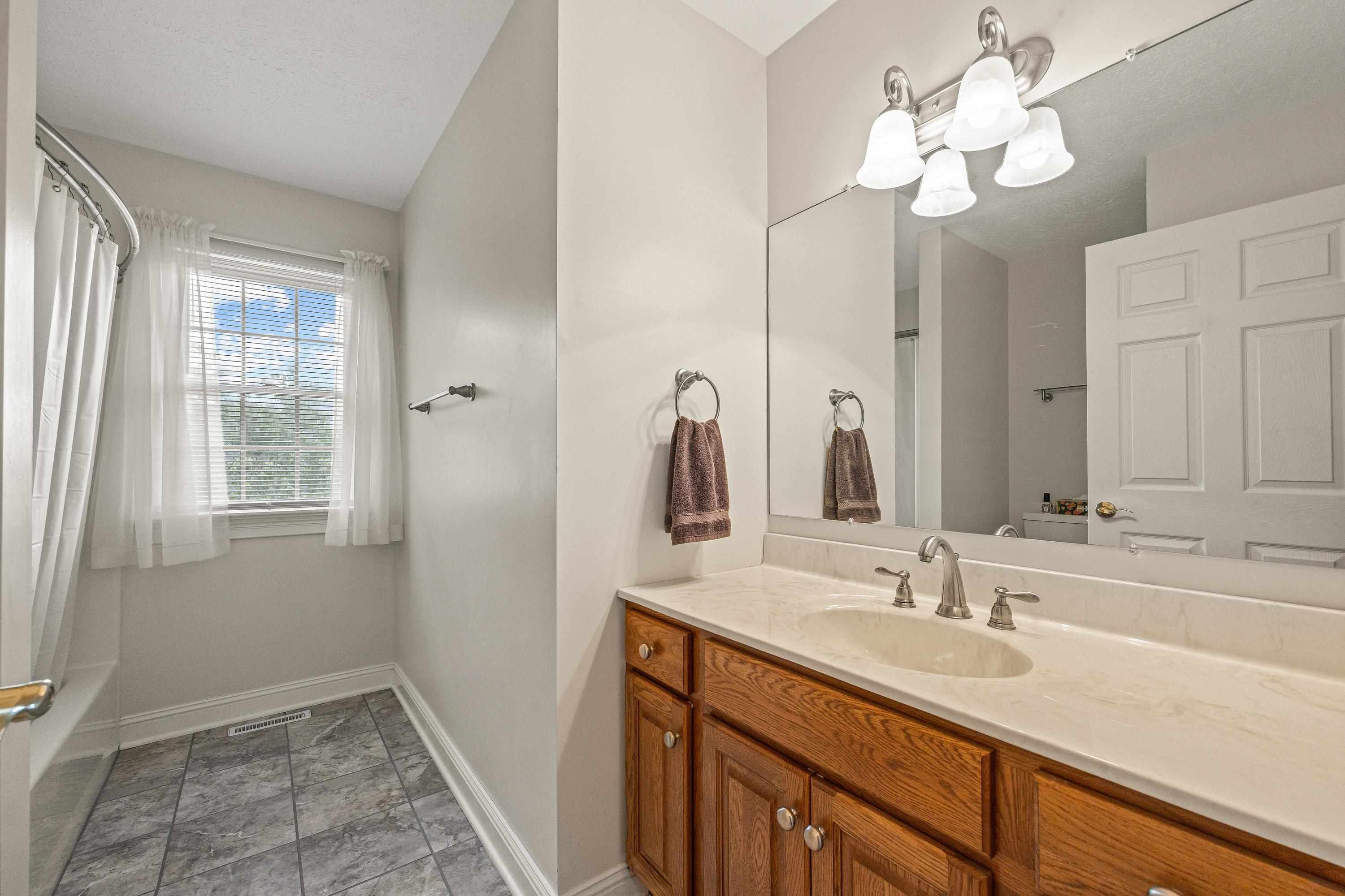 This large bathroom offers an oversized vanity and full bathtub/shower combination.  This space also features a vanity with storage cabinetry.