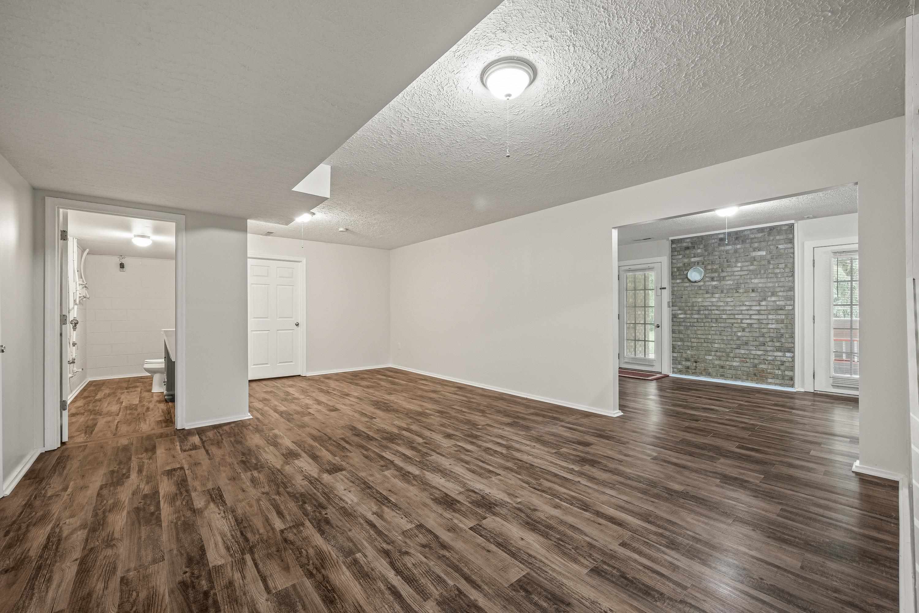 This large space, located at the bottom of the steps to the basement can be used for a varity of purposes including an exercise room, play space, etc.  This room features luxury vinyl plank, recessed lighting, and an attached 1/2 bathroom.