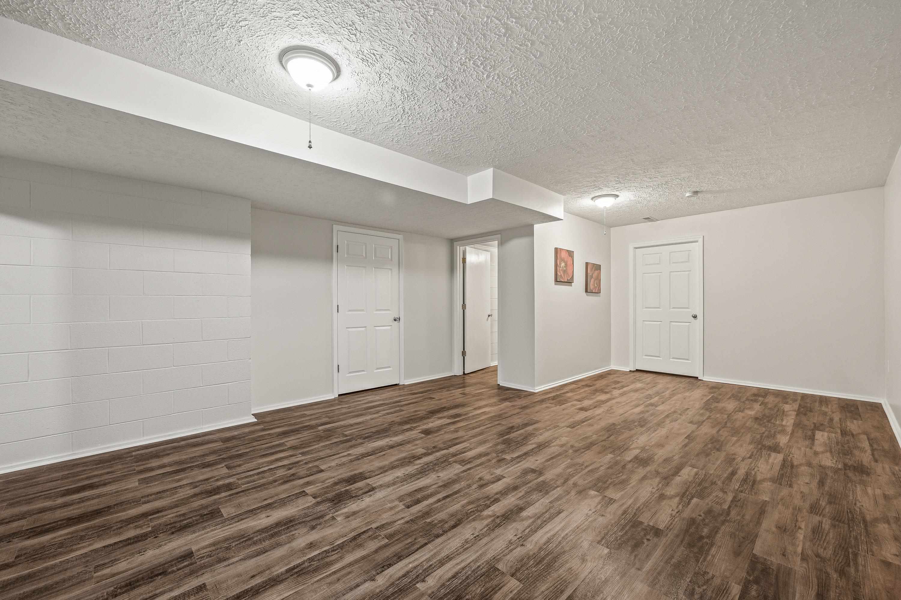 This large space, located at the bottom of the steps to the basement can be used for a varity of purposes including an exercise room, play space, etc.  This room features luxury vinyl plank, recessed lighting, and an attached 1/2 bathroom.