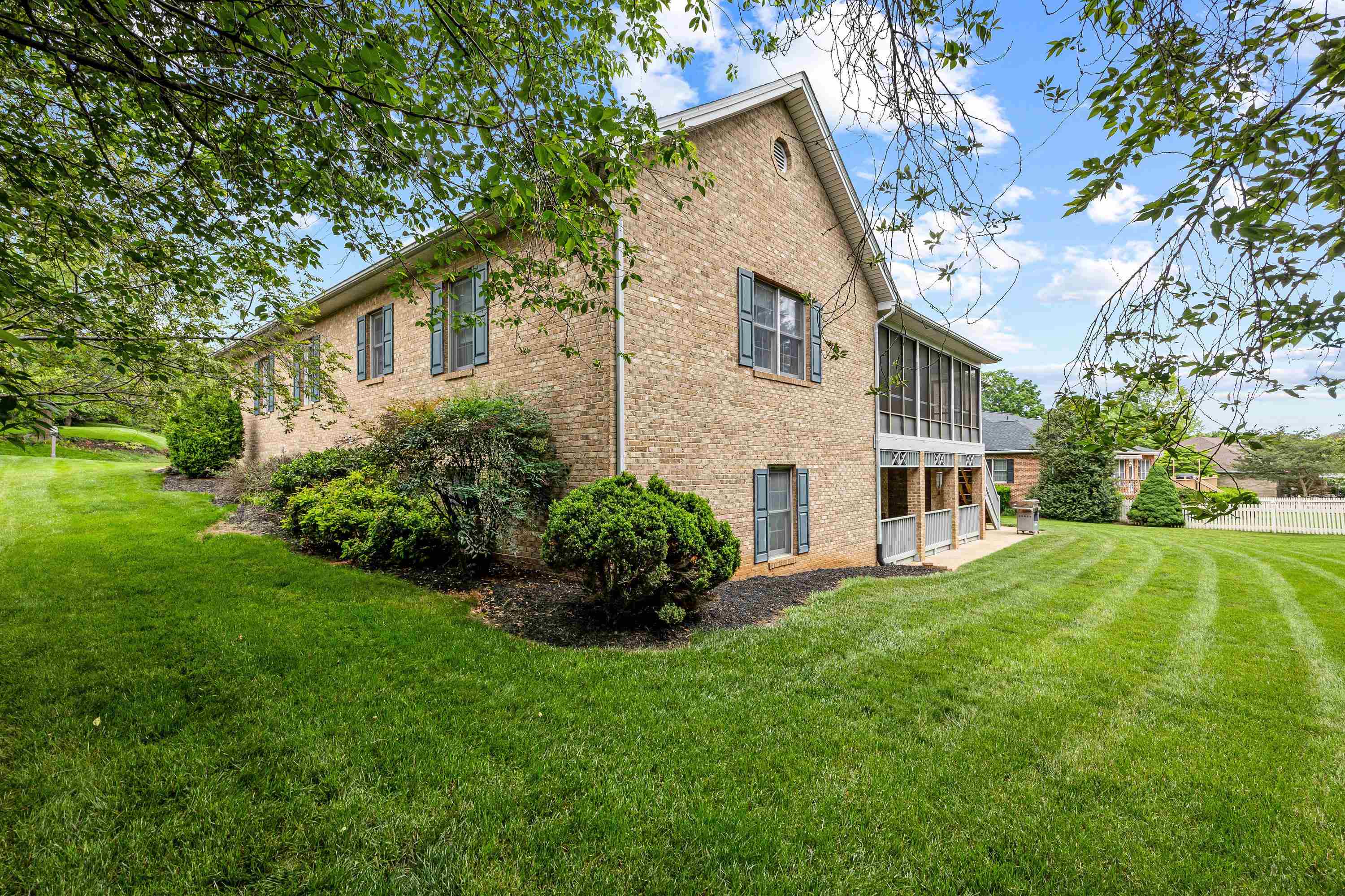 The rear view of the home highlights the mature yard and landscaping surrounding the home.  The large screened-in porch and deck are also highlights of this backyard area.