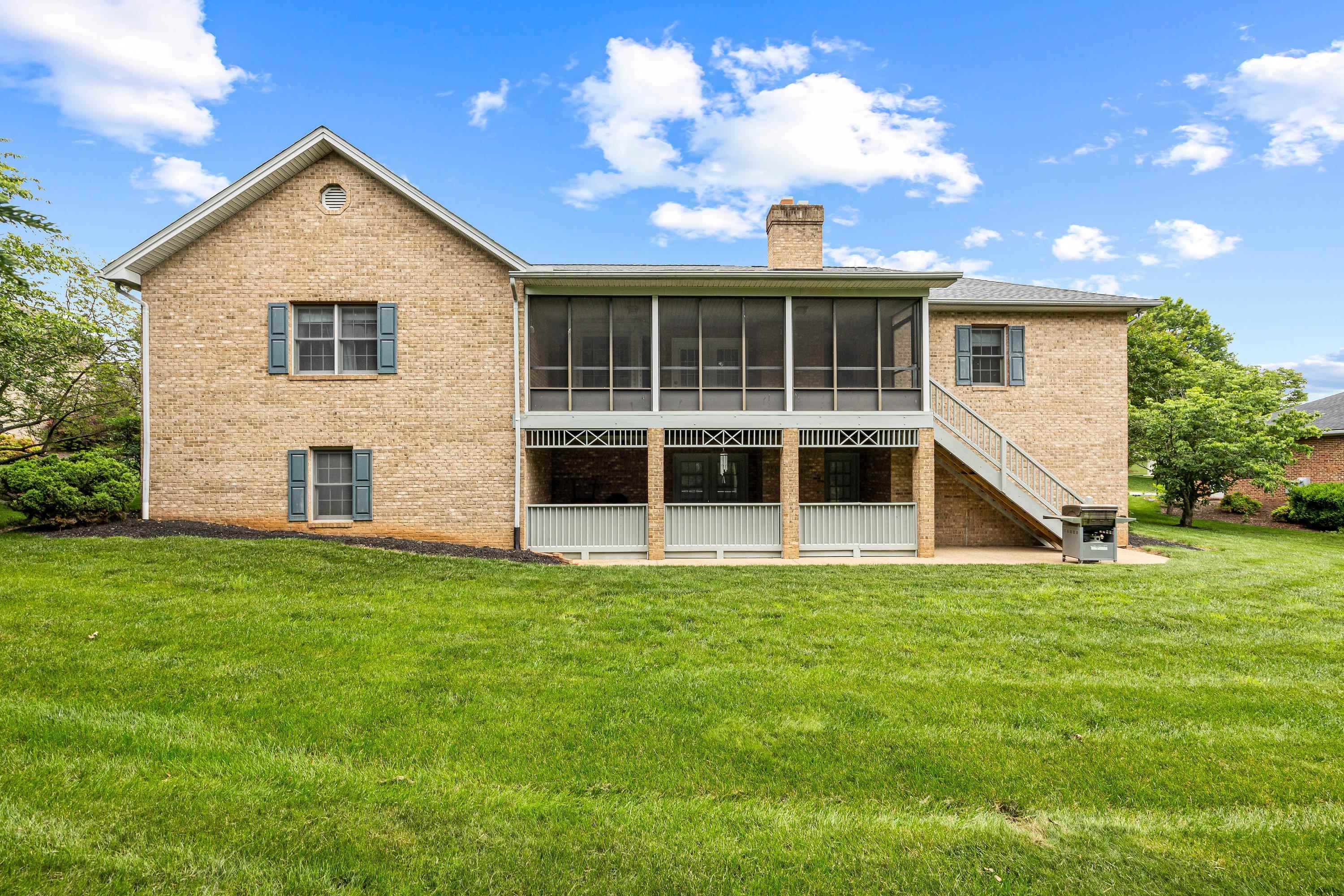 The rear view of the home highlights the mature yard and landscaping surrounding the home.  The large screened-in porch and deck are also highlights of this backyard area.