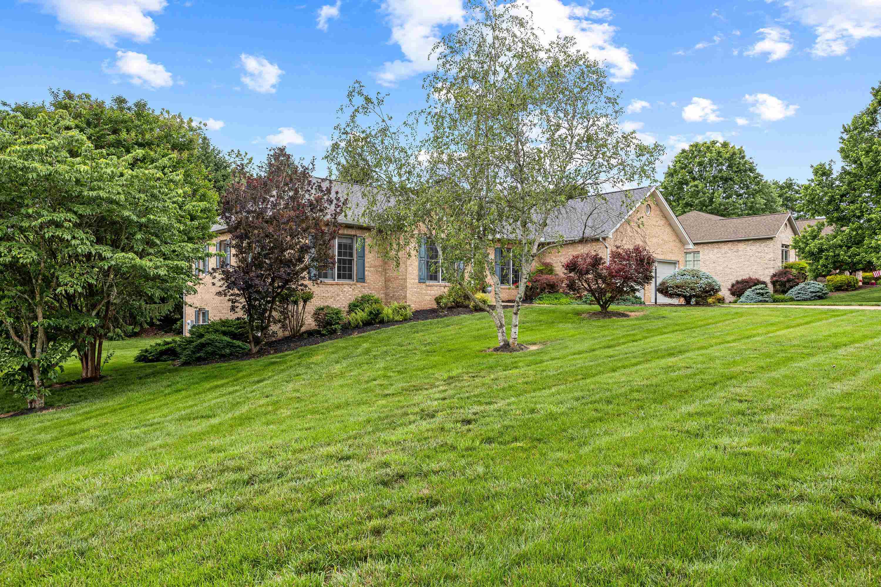 The rear view of the home highlights the mature yard and landscaping surrounding the home.  The large screened-in porch and deck are also highlights of this backyard area.
