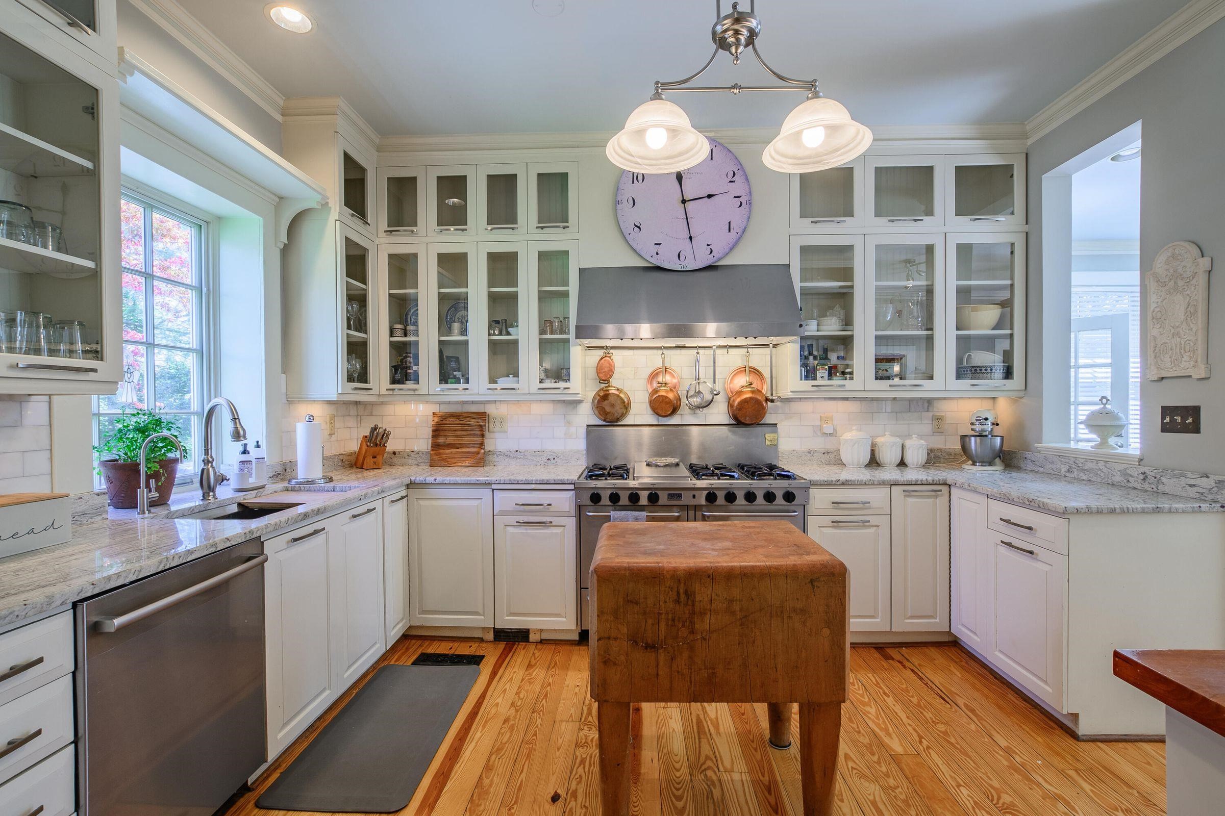 Marble counter tops surround the authentic butcher block. Light streams in the window. Endless cabinets.