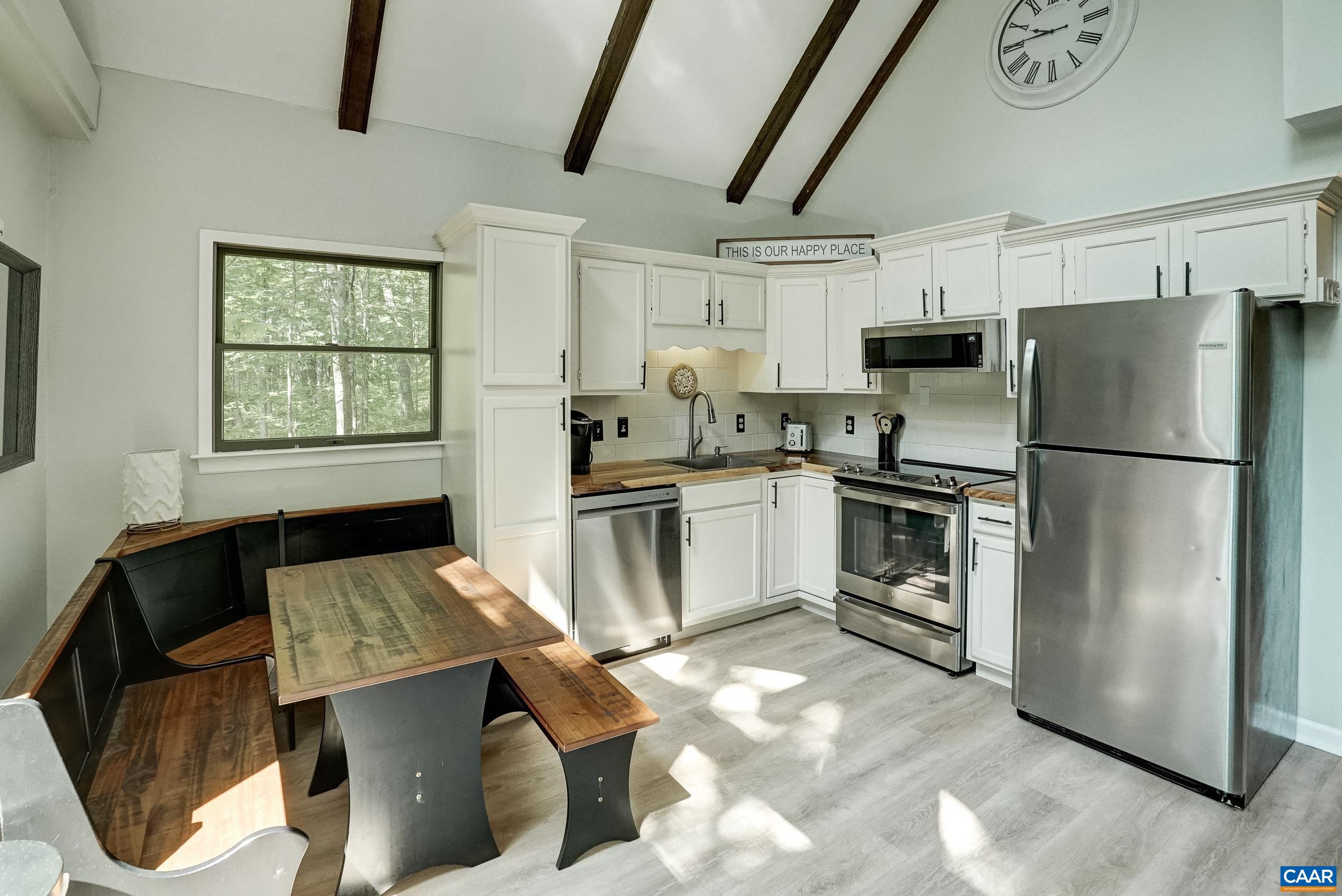 Renovated kitchen with live edge wood countertops, white cabinets and new stainless appliances.