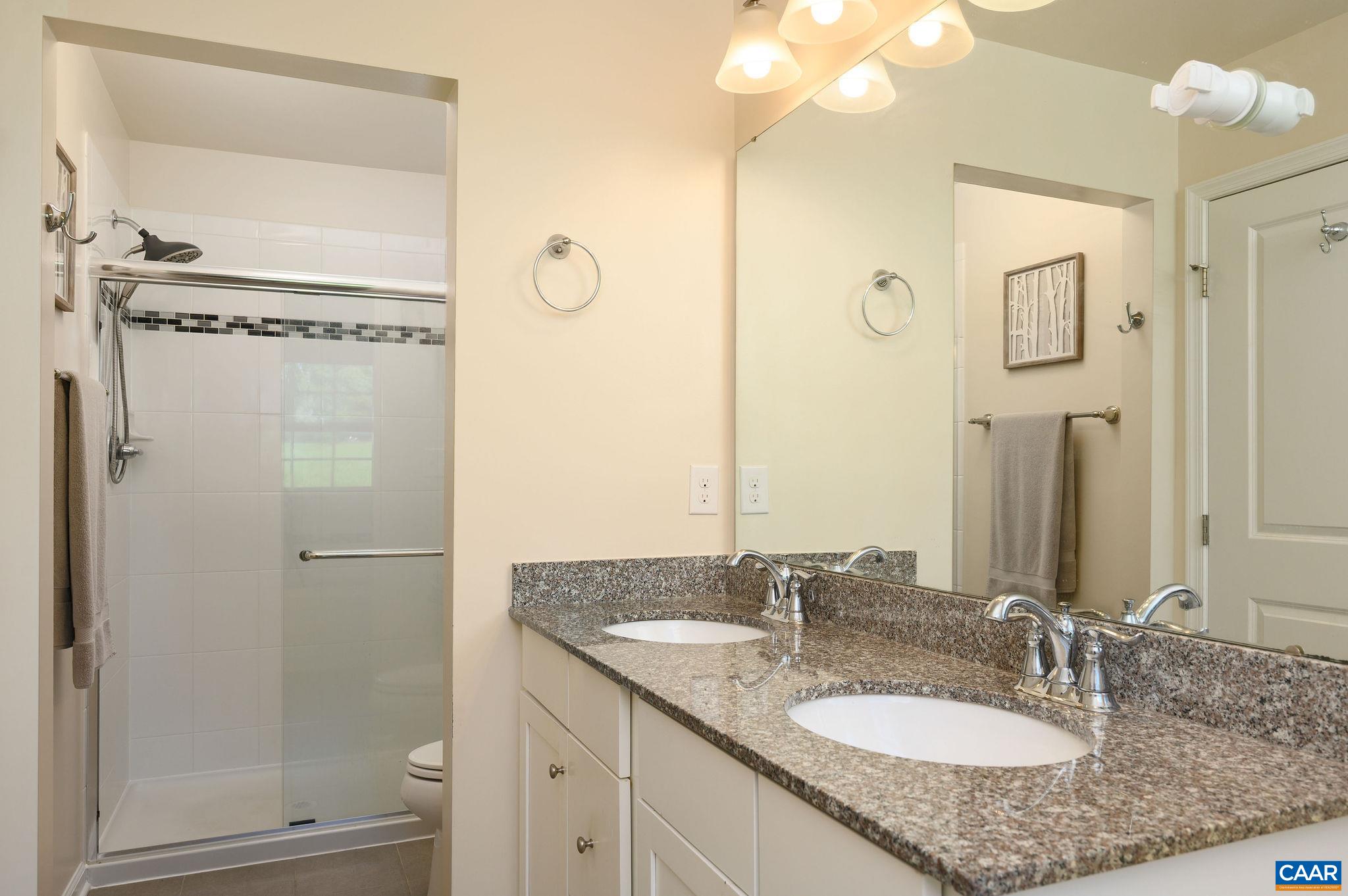 The tiled walk-in shower features new glass doors.