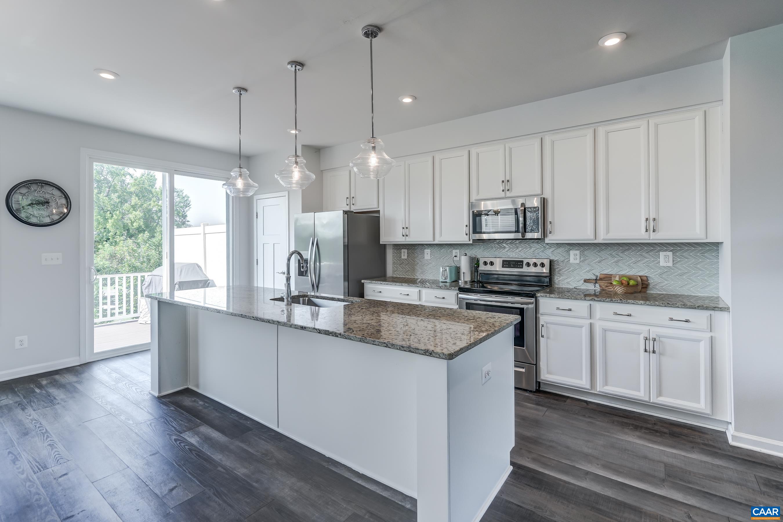 Kitchen features white cabinets, tile backsplash and granite countertops