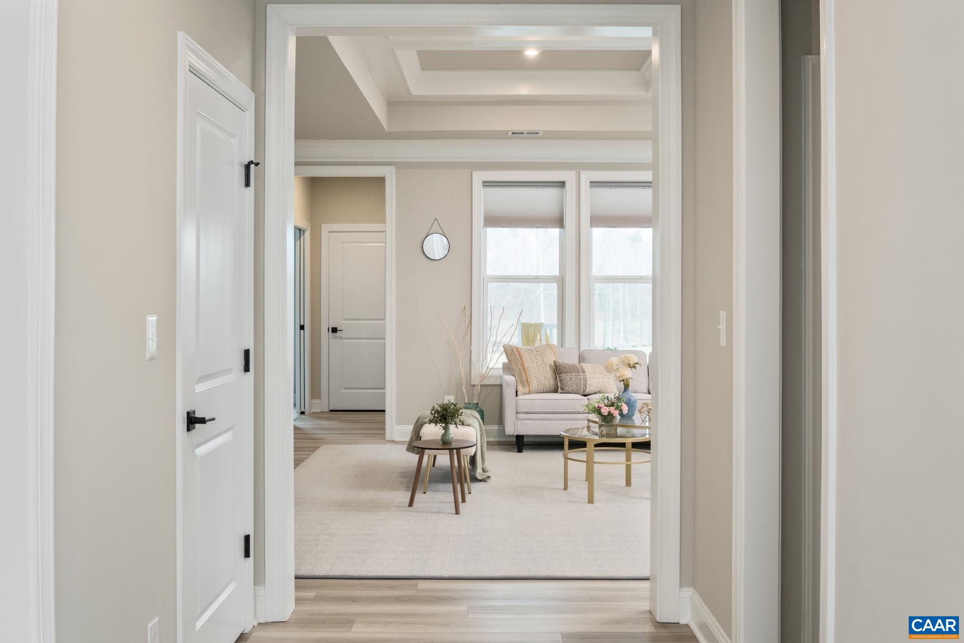 From the brightly lit foyer, the hallway leads you to an elegant living room that features a tray and coffered ceiling, a triple window overlooking the extended custom thermal bluestone porch, and the golf course.