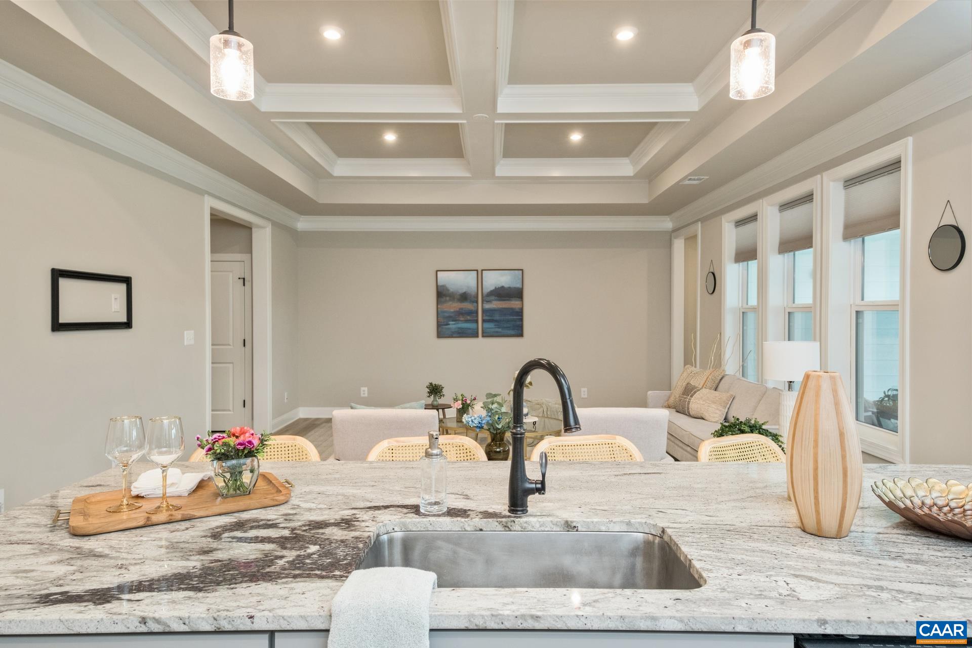 Beautiful view from the kitchen island to the living room with the tray and coffered ceiling.