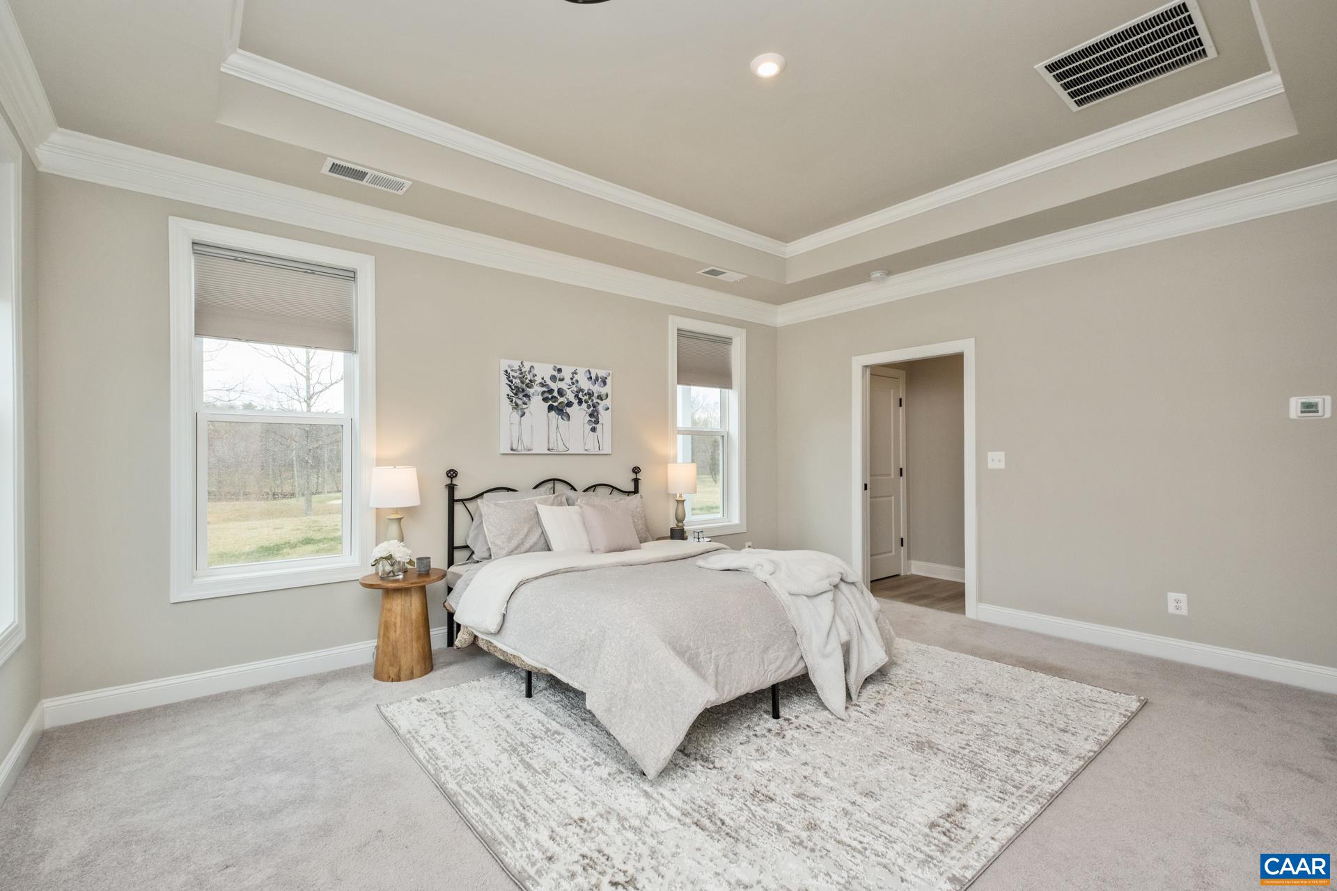 Elegance continues into the primary suite and features a raised tray ceiling with crown molding.  The primary suite is bright and spacious, and it overlooks the golf course.