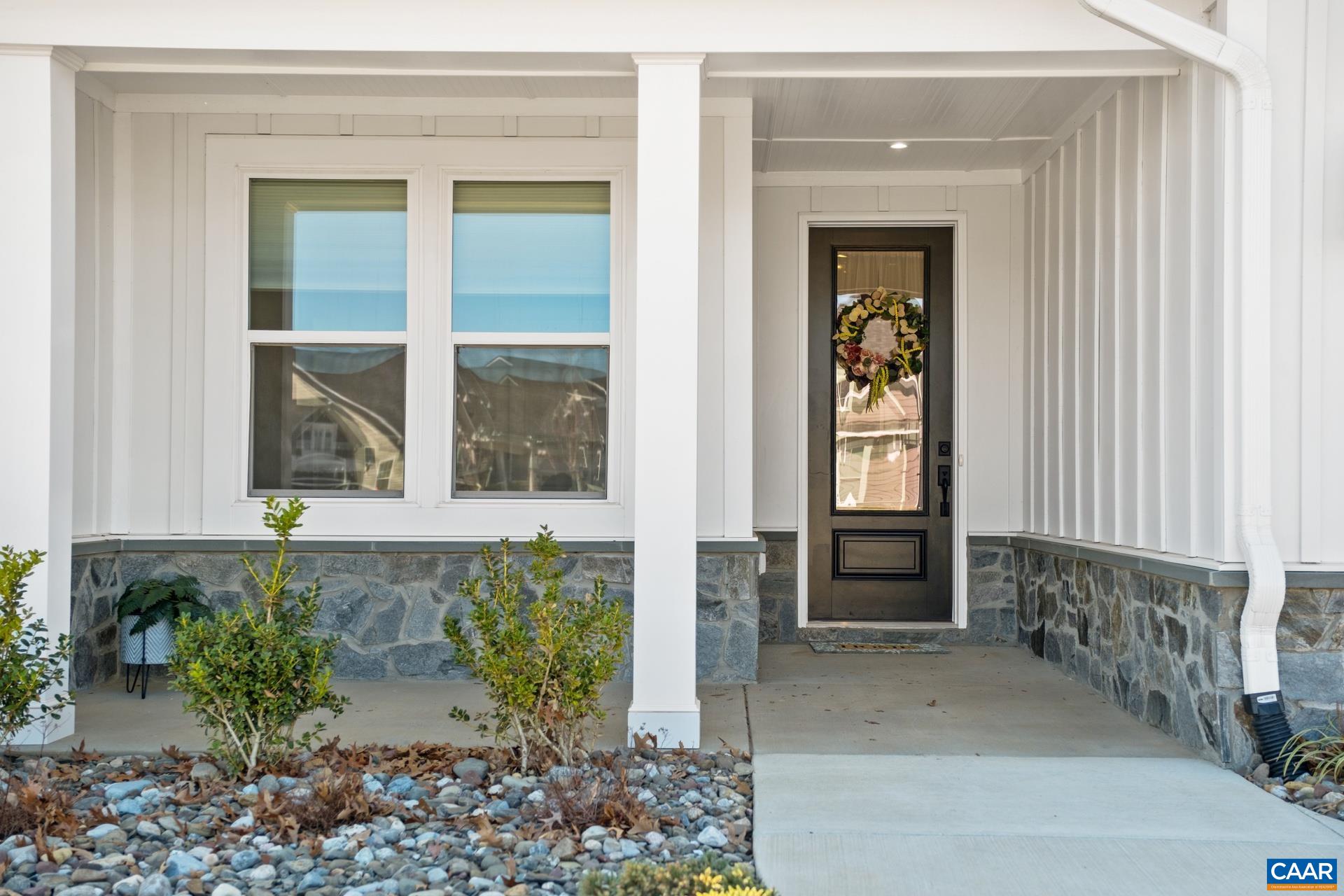 The covered front porch features exterior stone and columns.