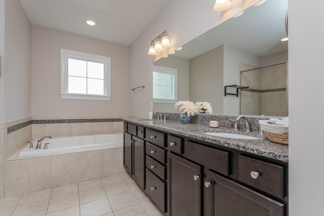 featuring double sinks,tile floor, granite countertops, tub, walk-in shower and bidet