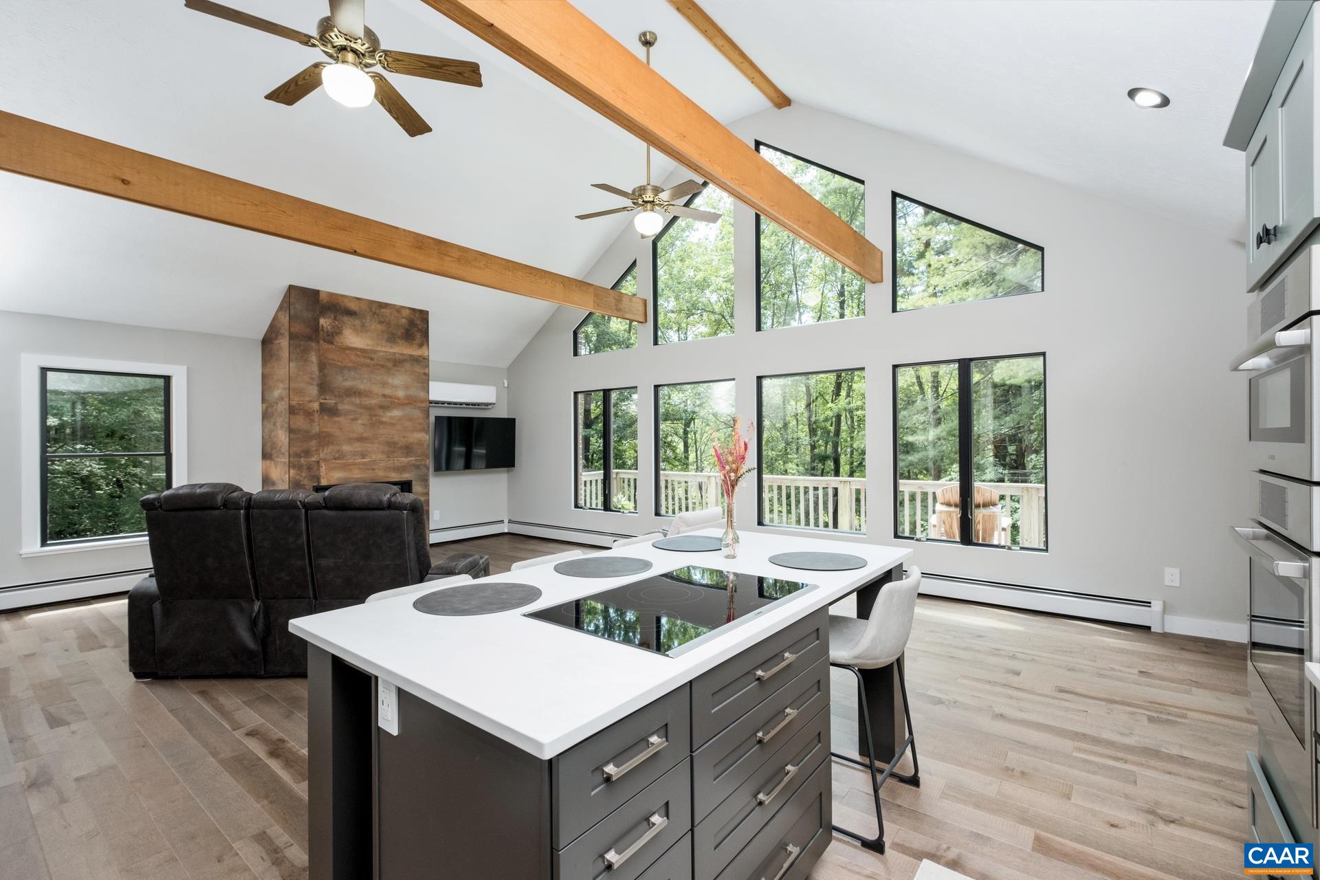 The kitchen and great room are open, with soaring windows to let in plenty of natural light, exposed wood beams, and a new linear gas fireplace with new floor-to-ceiling surround.