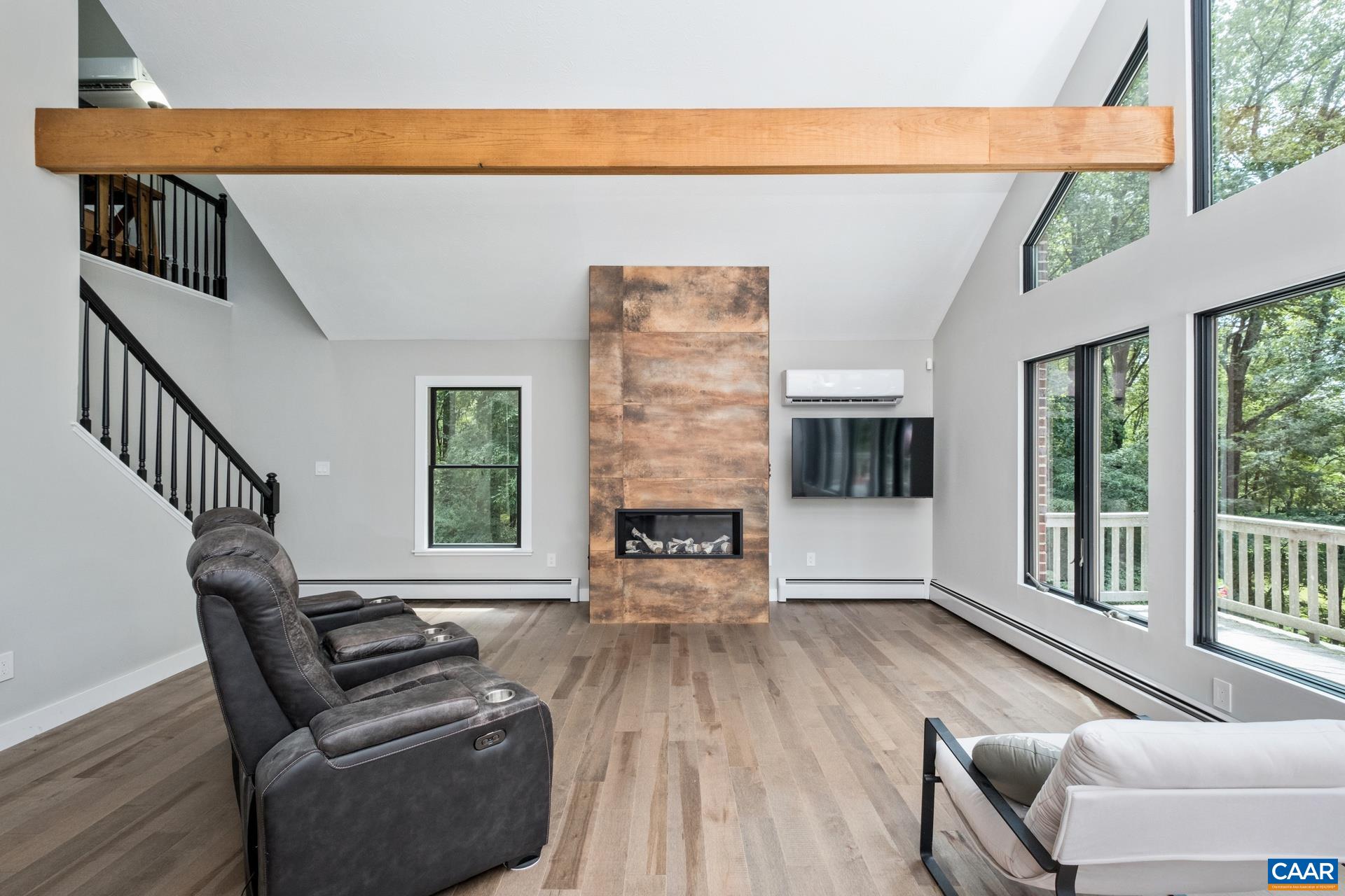 The kitchen and great room are open, with solid maple flooring, soaring windows to let in plenty of natural light, exposed wood beams, and a new linear gas fireplace with new floor-to-ceiling surround.