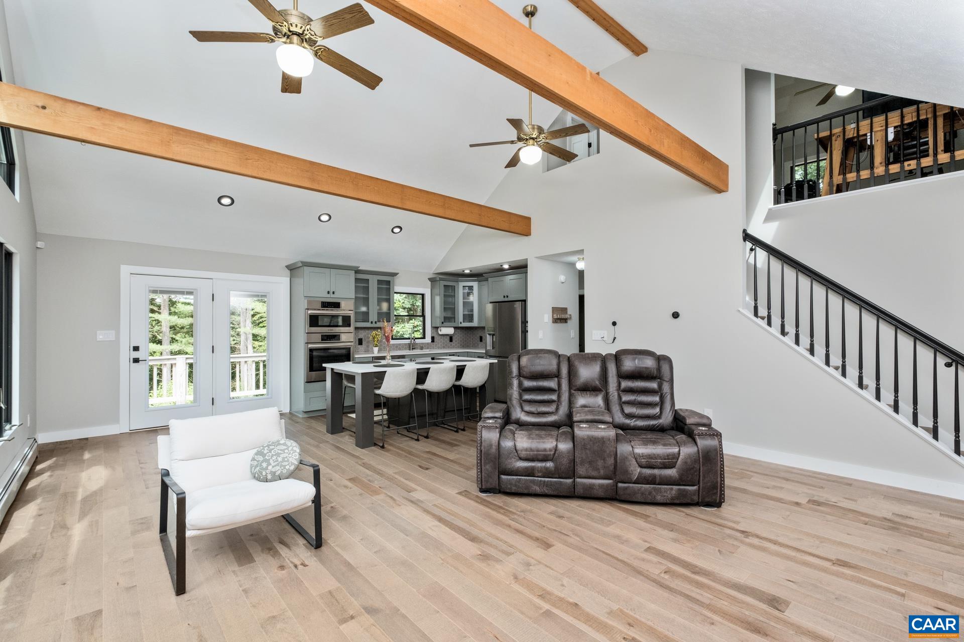 The kitchen and great room are open, with soaring windows to let in plenty of natural light, exposed wood beams, recessed lighting, and solid maple flooring.