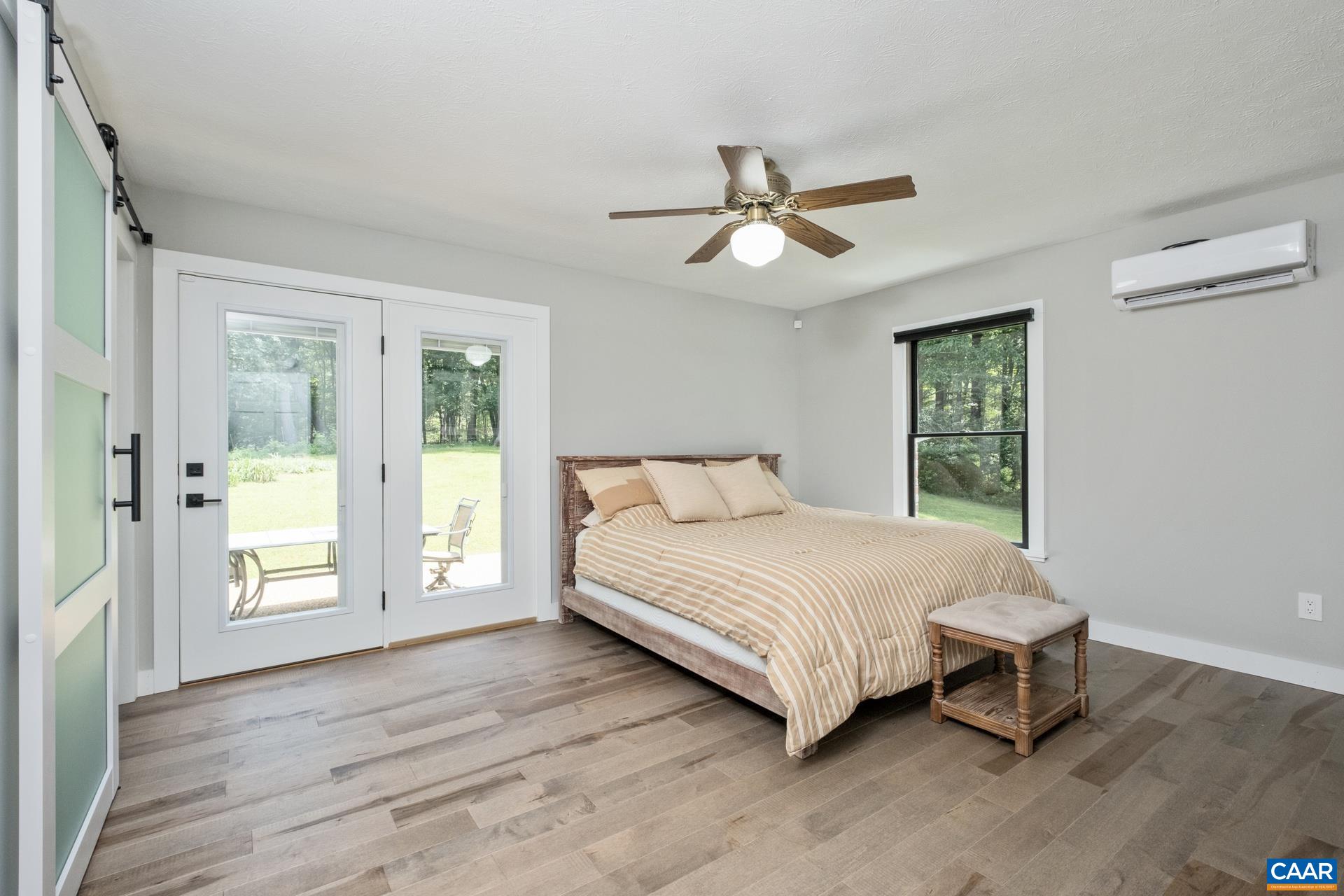 The primary suite is on the main level, and features solid maple flooring and barn door style closet doors. The glass panel exterior door allows in plenty of natural light and opens to the patio.