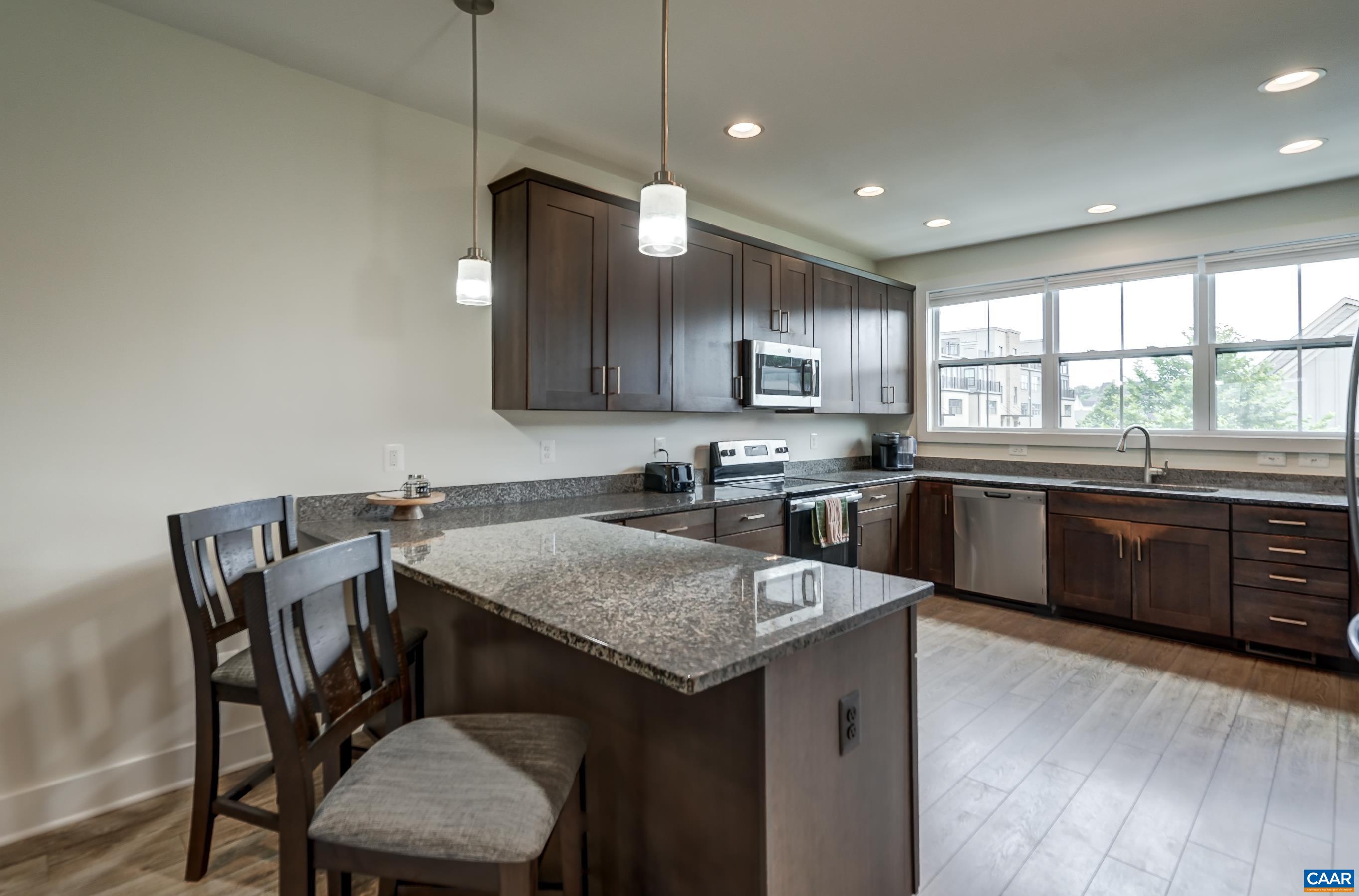 Light-filled kitchen with granite coutnertops and bar seating.