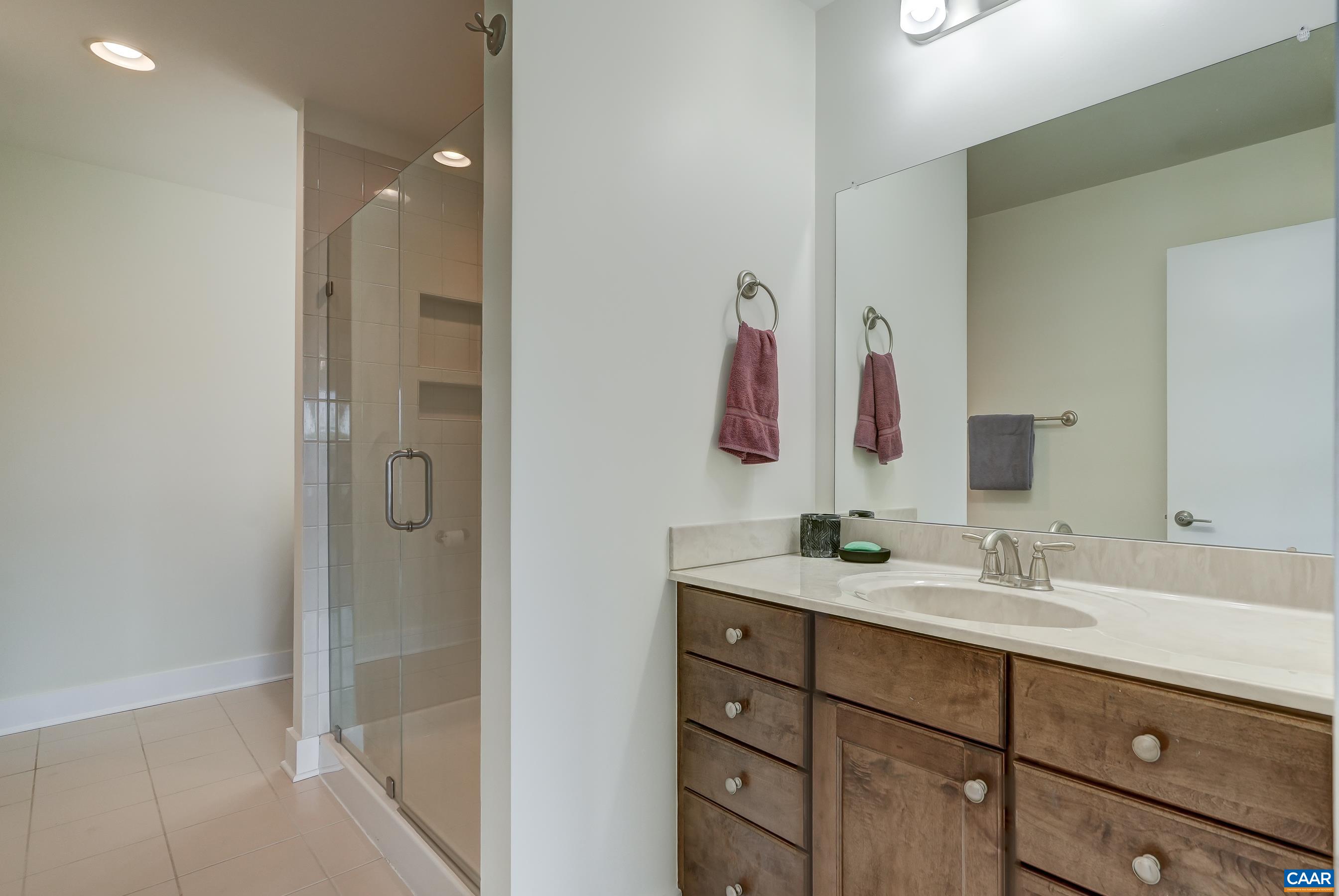 Primary bathroom features two separate vanities and frameless glass, tiled shower.
