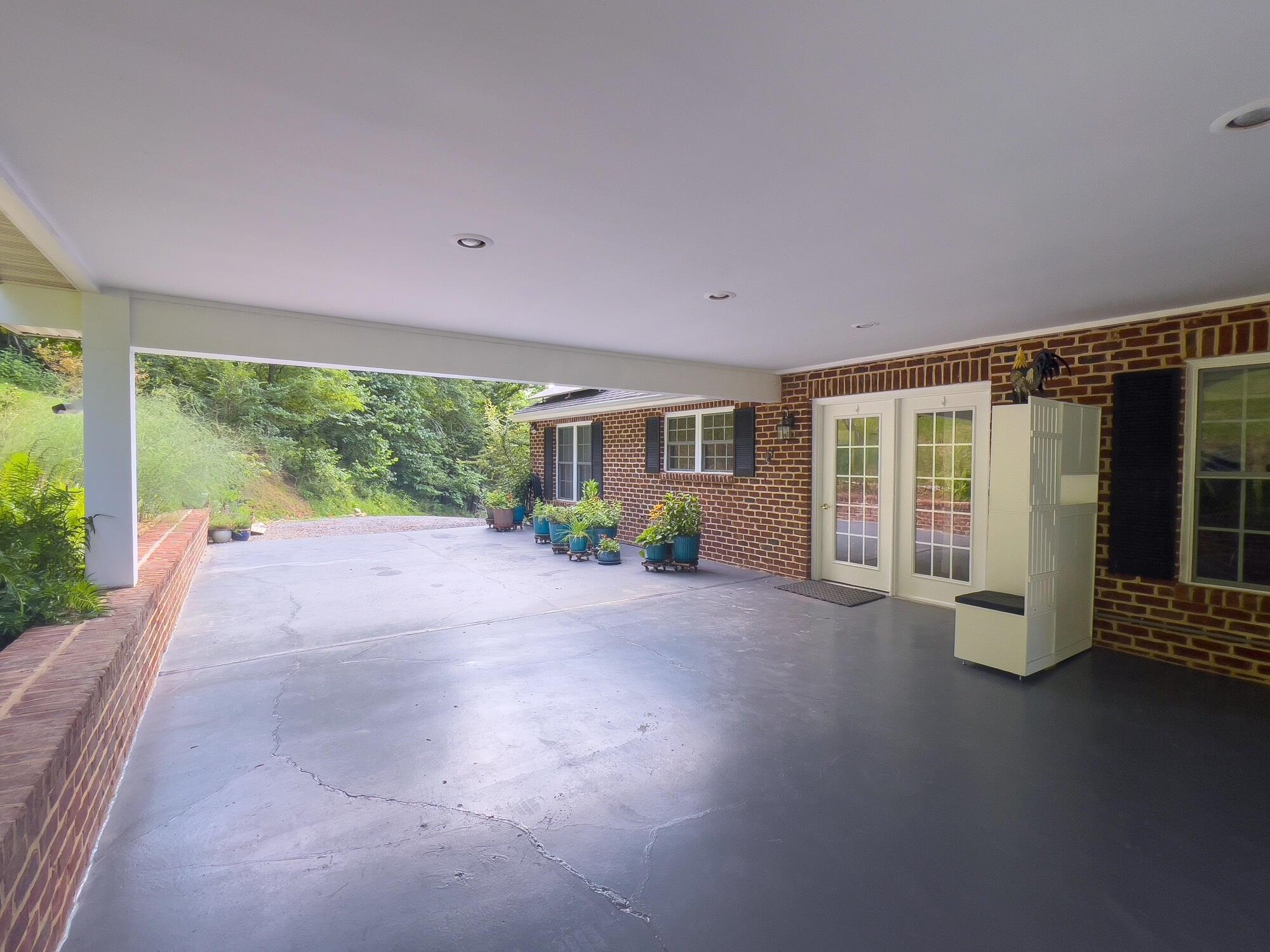 Large Carport with doors leading to Kitchen. Concrete painted 07/25.