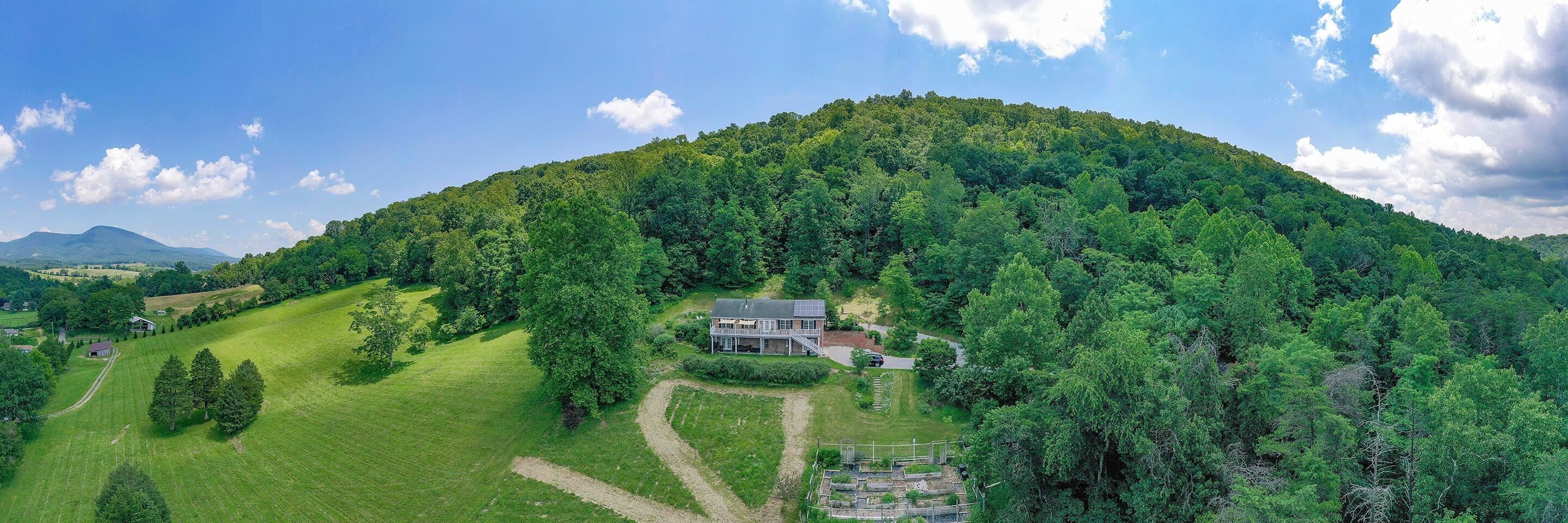 825 Still House Pano of House  Drone looking back at the 9.40-acre property. Showing several gardens and landscaping.