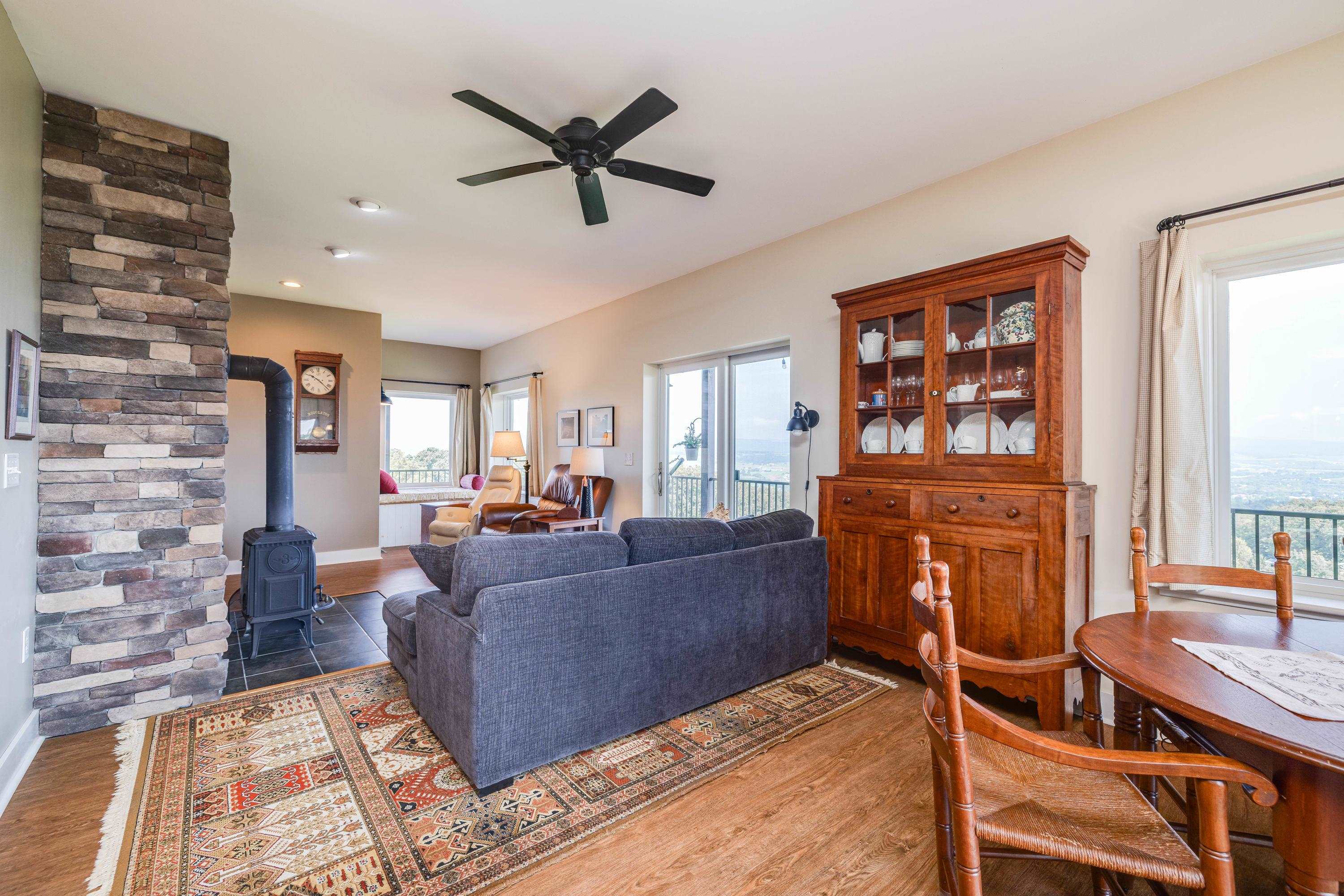 The large living room features expansive windows overlooking the front porch and the beautiful front yard views the home offers.  This space contains a wood stove, hardwood flooring, ceiling fan, and lots of space for gathering with family and friends.