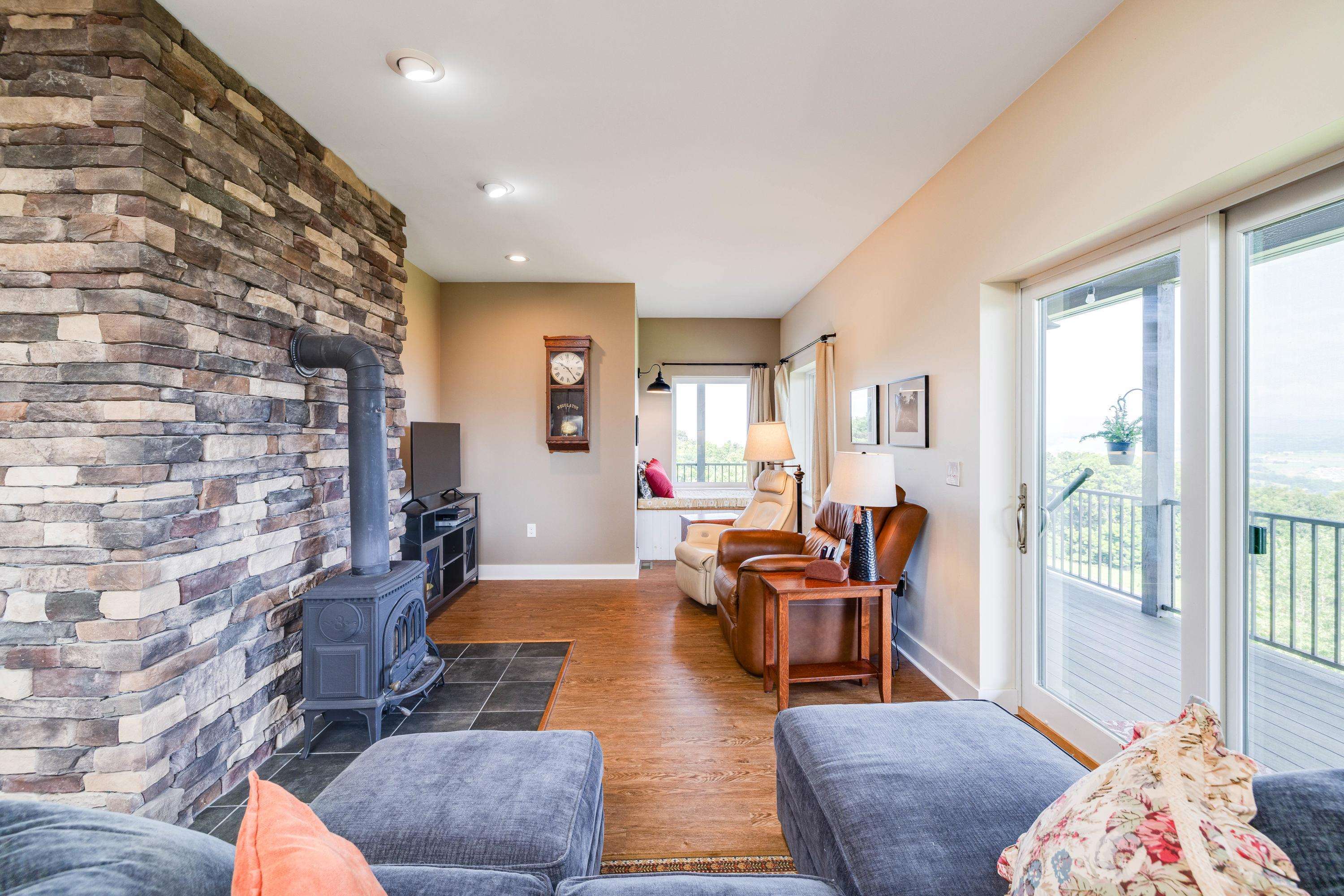 The large living room features expansive windows overlooking the front porch and the beautiful front yard views the home offers.  This space contains a wood stove, hardwood flooring, ceiling fan, and lots of space for gathering with family and friends.