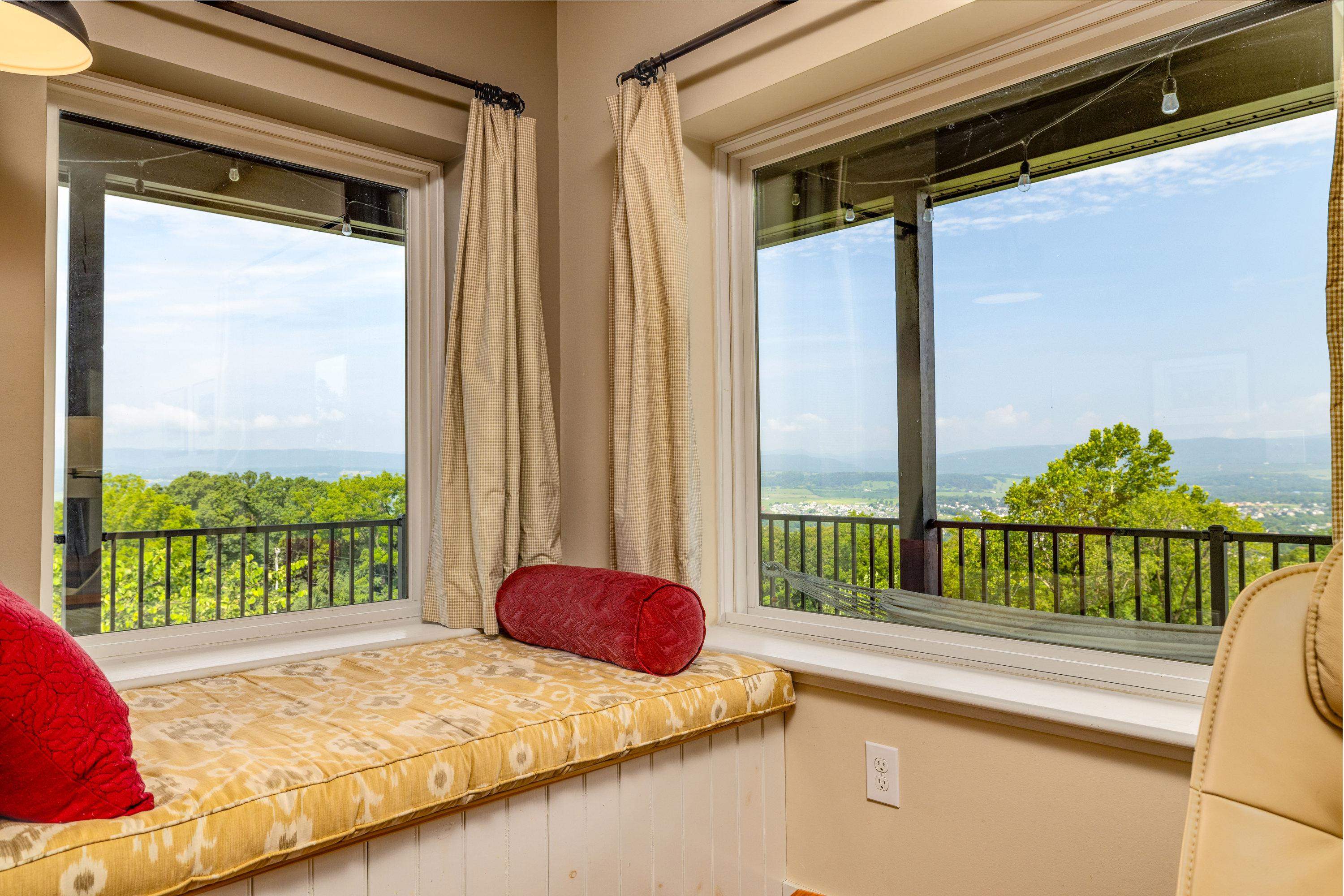 The large living room features expansive windows overlooking the front porch and the beautiful front yard views the home offers.  This space contains a wood stove, hardwood flooring, ceiling fan, and lots of space for gathering with family and friends.