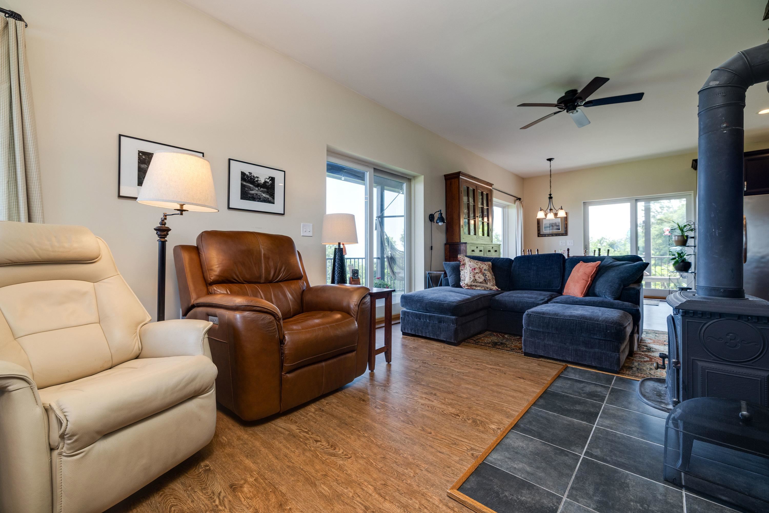 The large living room features expansive windows overlooking the front porch and the beautiful front yard views the home offers.  This space contains a wood stove, hardwood flooring, ceiling fan, and lots of space for gathering with family and friends.
