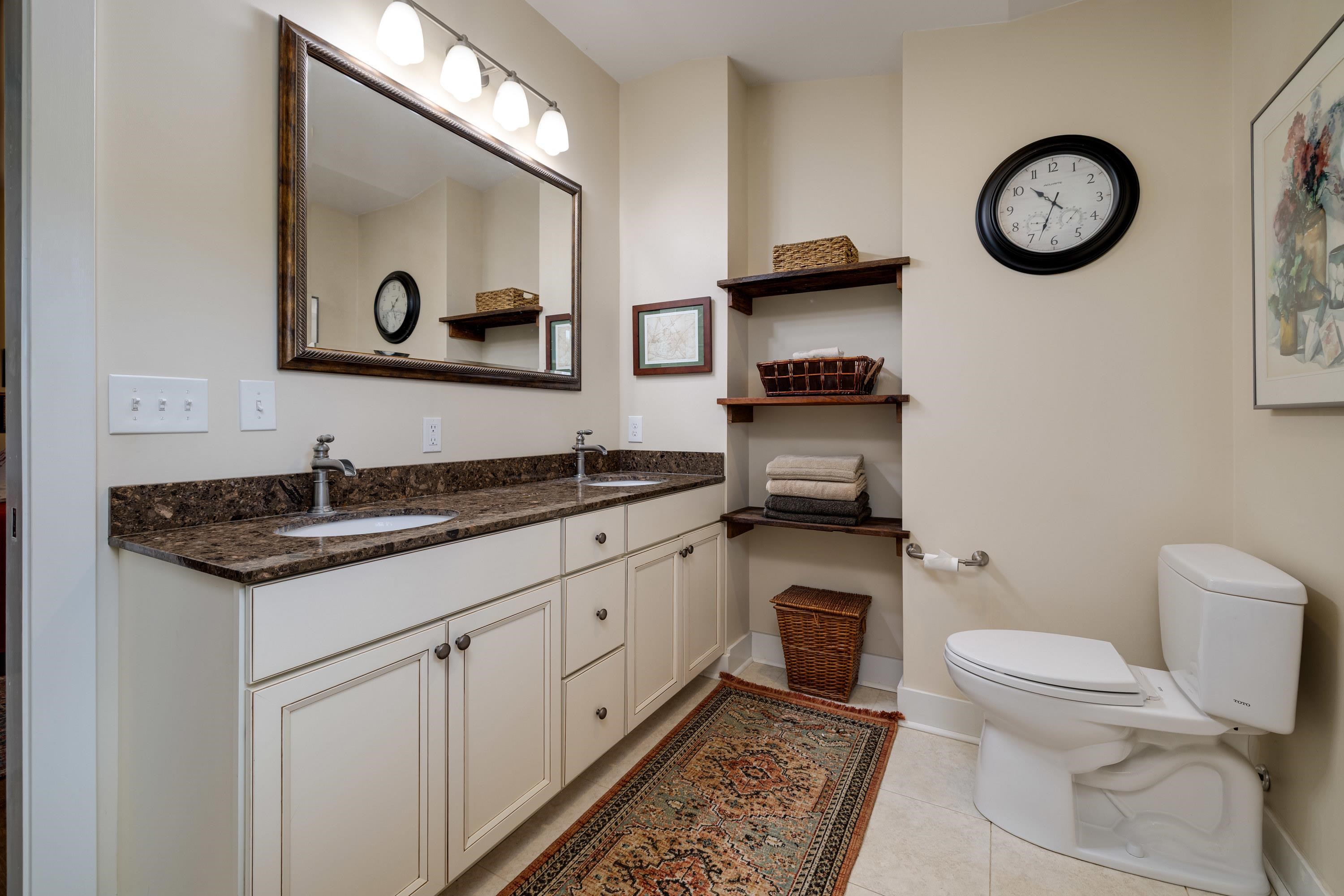 This full bathroom features dual vanities, tile shower, tile flooring, and lots of storage cabinetry.