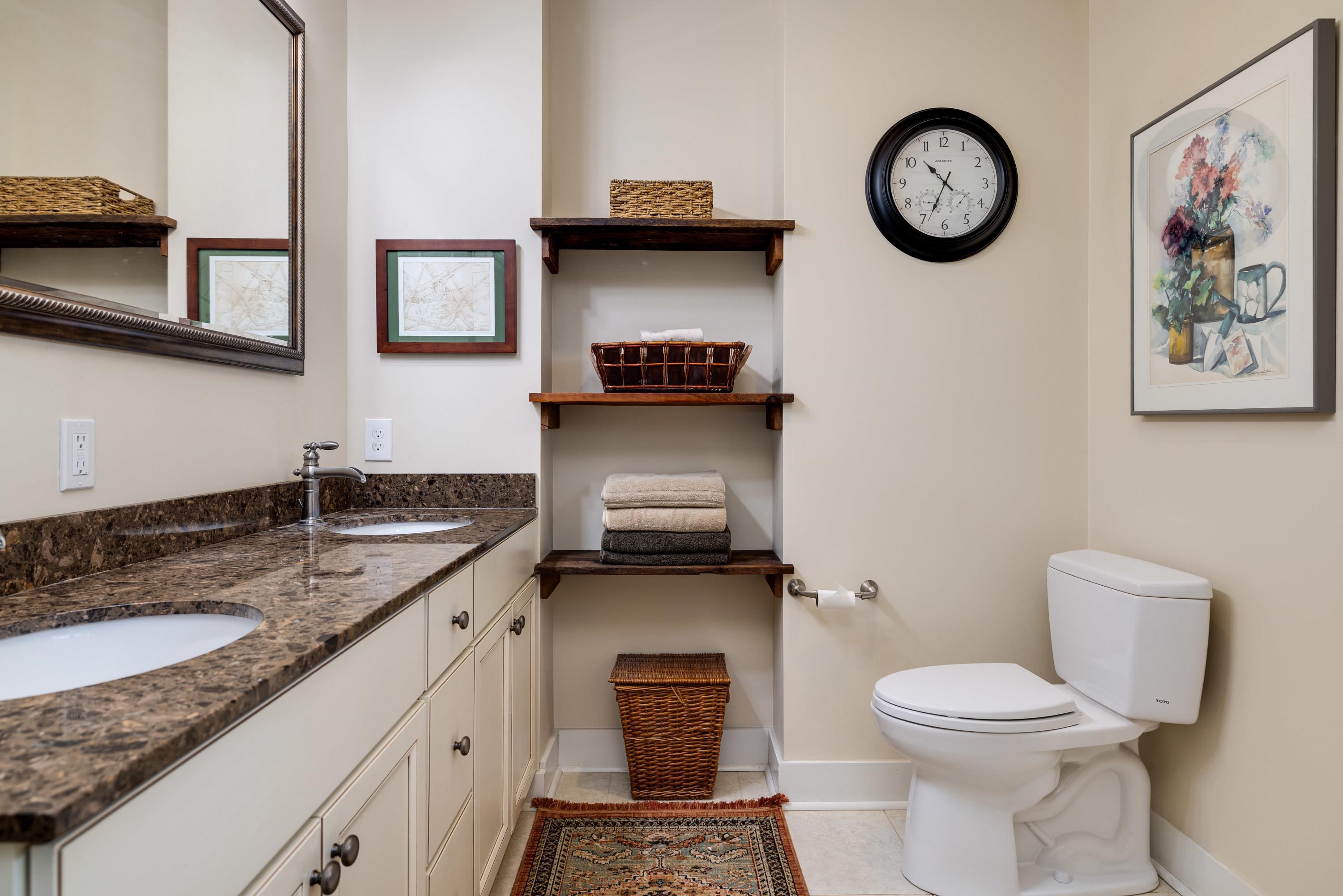 This full bathroom features dual vanities, tile shower, tile flooring, and lots of storage cabinetry.